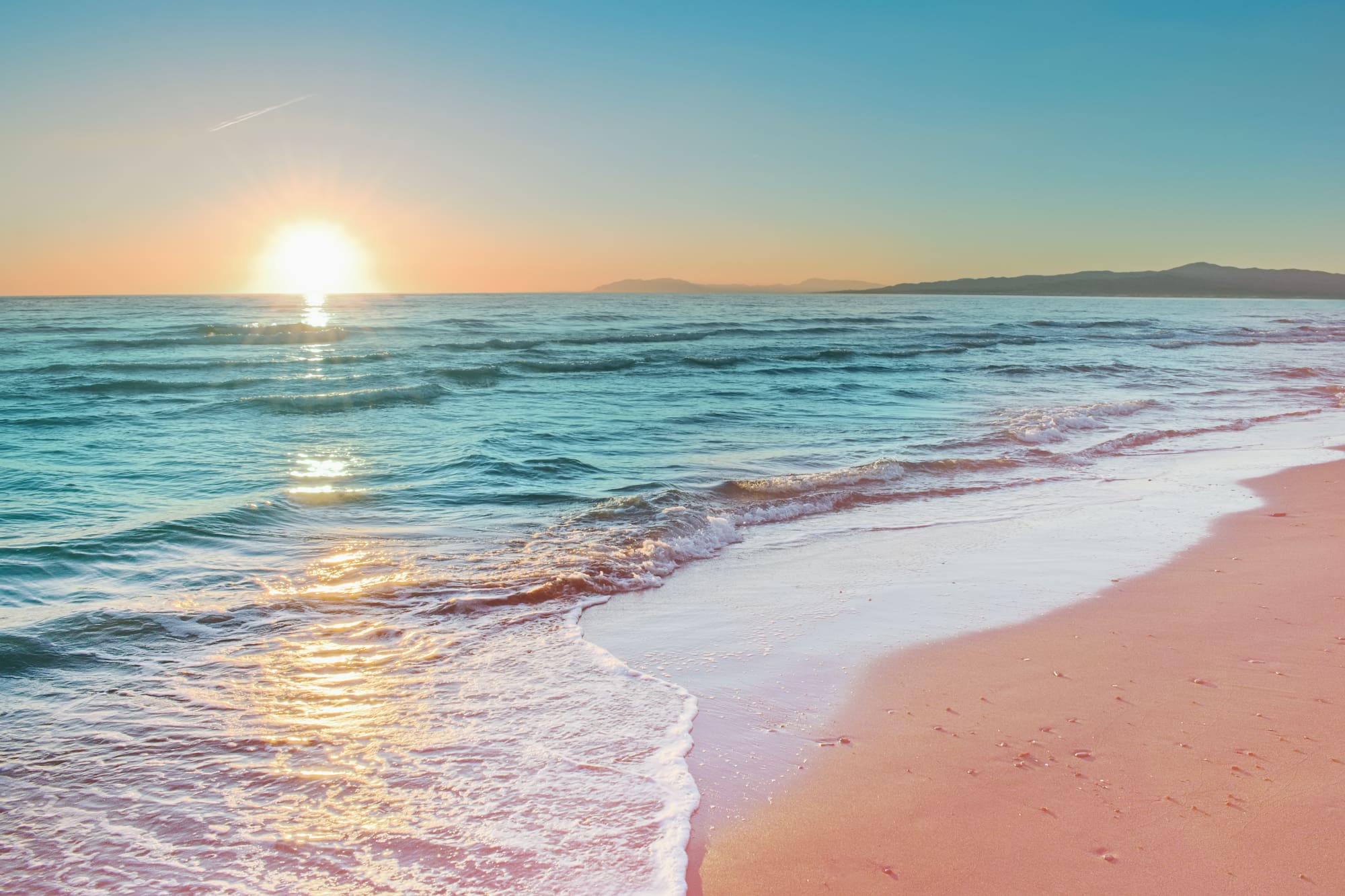 a beach with waves and a sunset