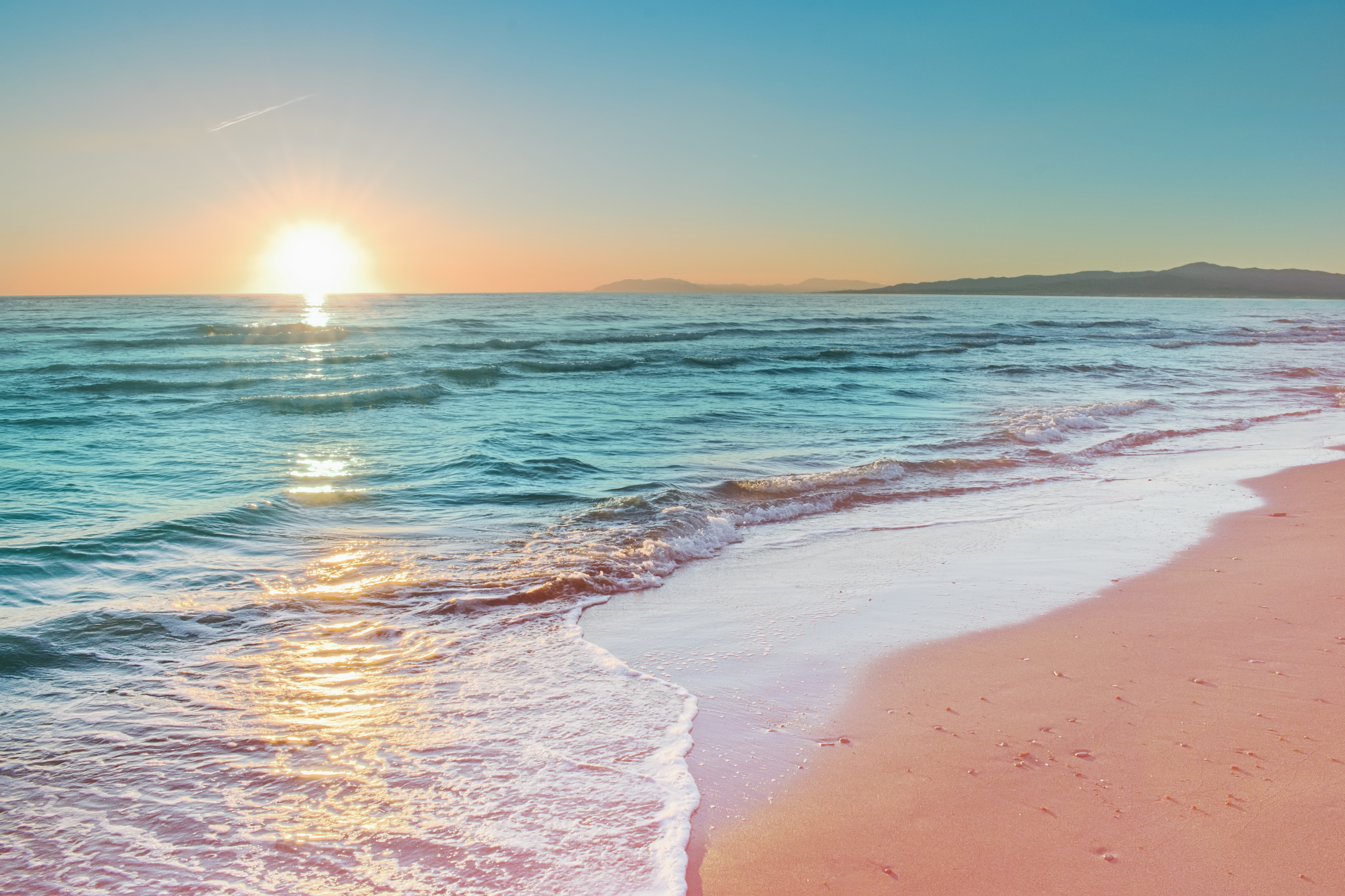 a beach with waves and a sunset