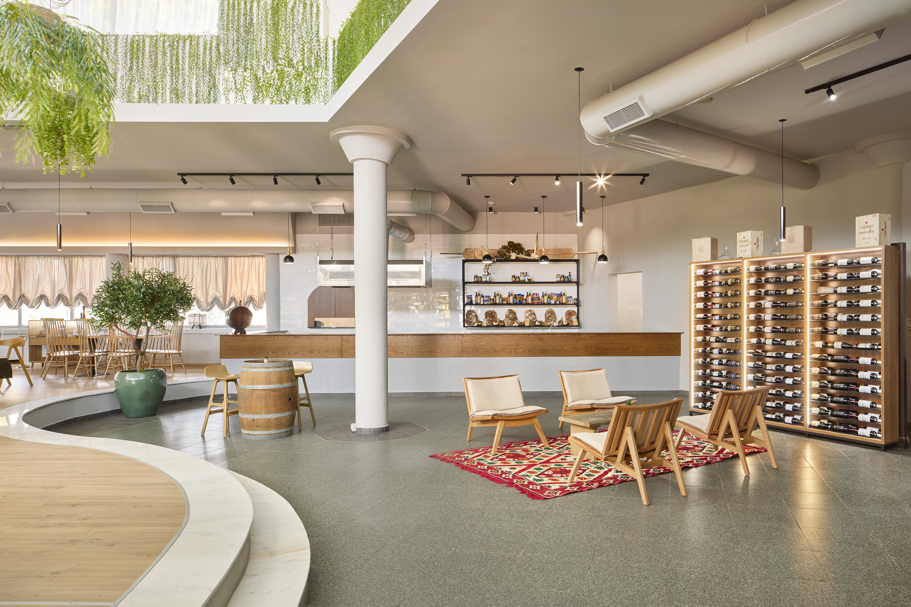 Modern wine bar with green plants, lounge seating, and illuminated wine display.