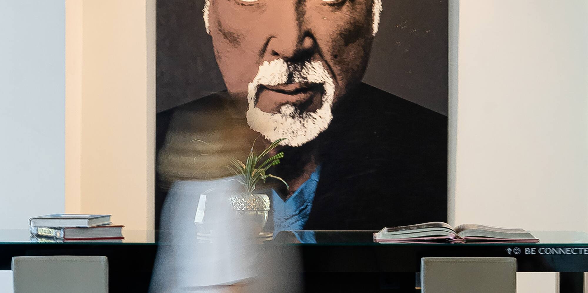 a person walking in front of a painting of a man