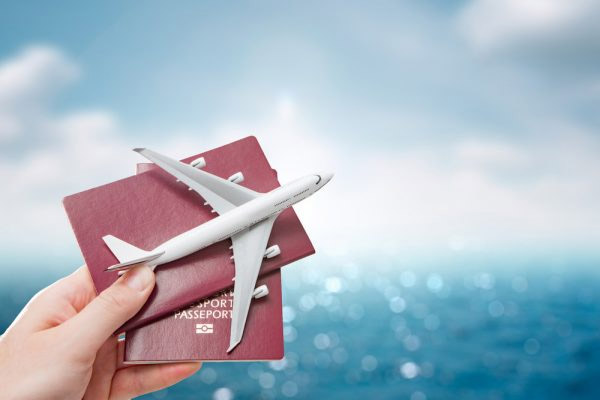 Hand holding passports and airplane model for international travel.