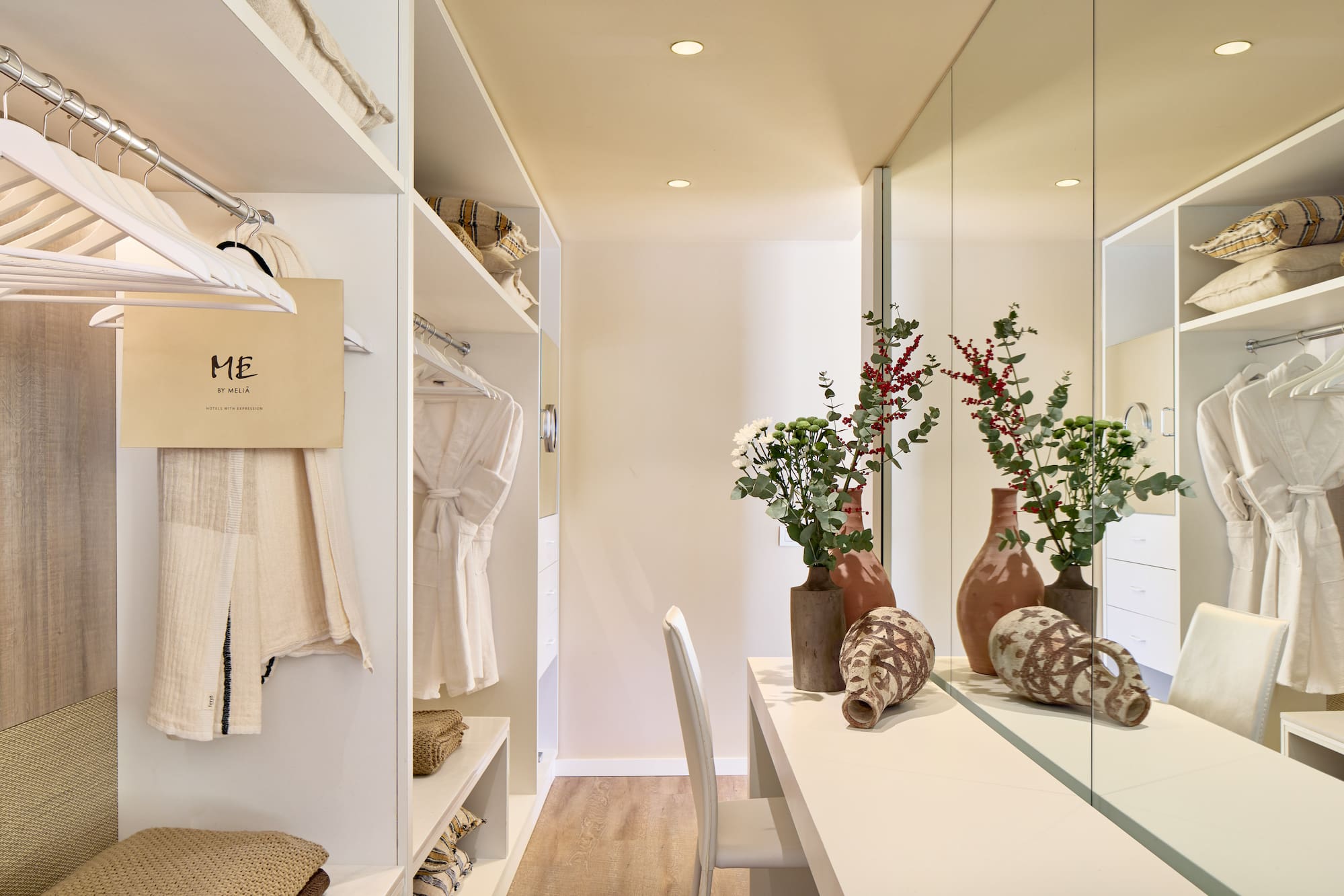a room with a mirror and shelves with vases and flowers