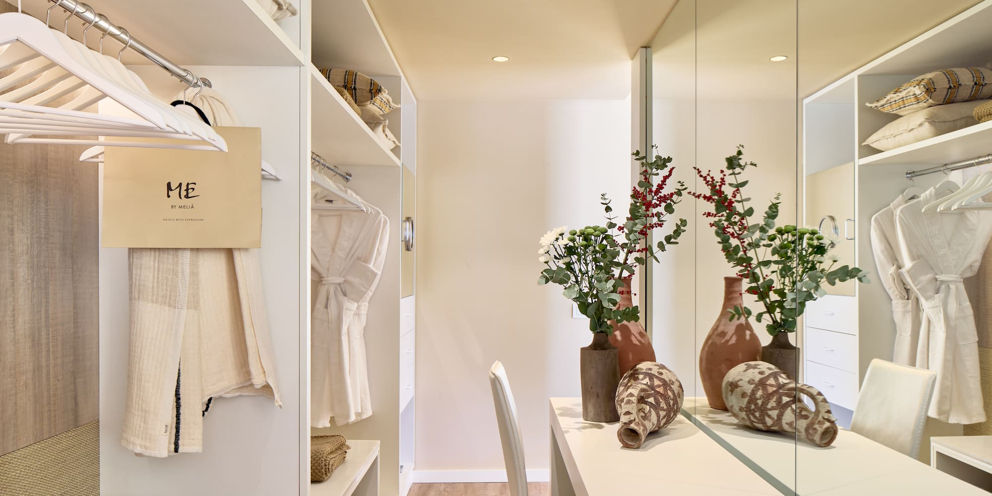 a room with a mirror and shelves with vases and flowers