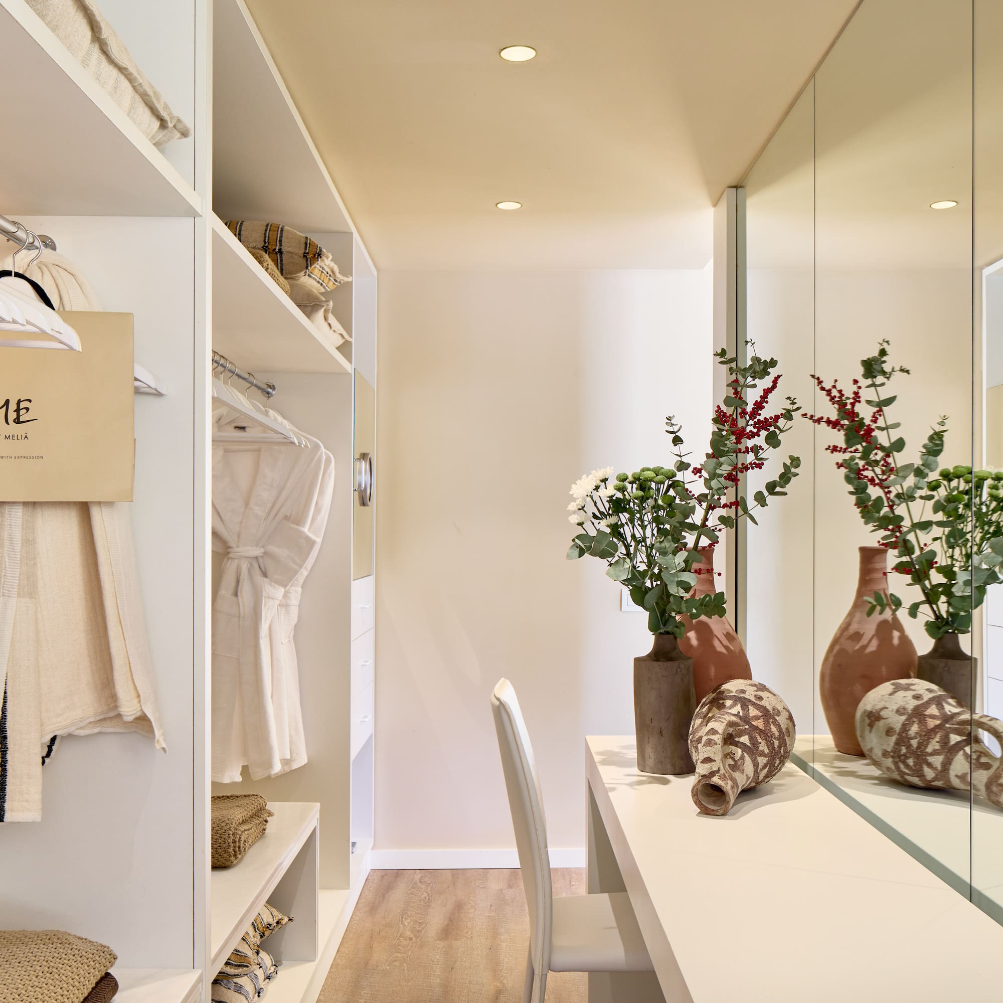 a room with a mirror and shelves with vases and flowers