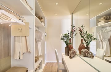 a room with a mirror and shelves with vases and flowers