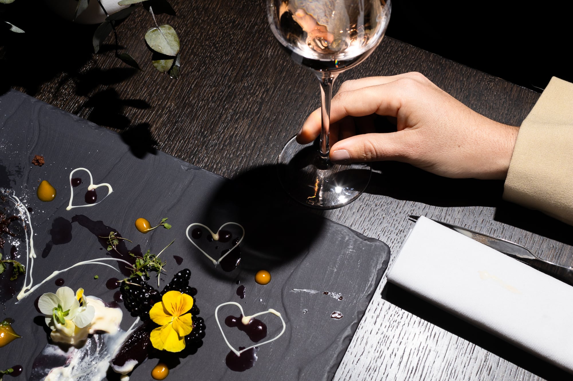 Elegant dessert platter featuring berries, pansies, cream hearts, and a wine glass.