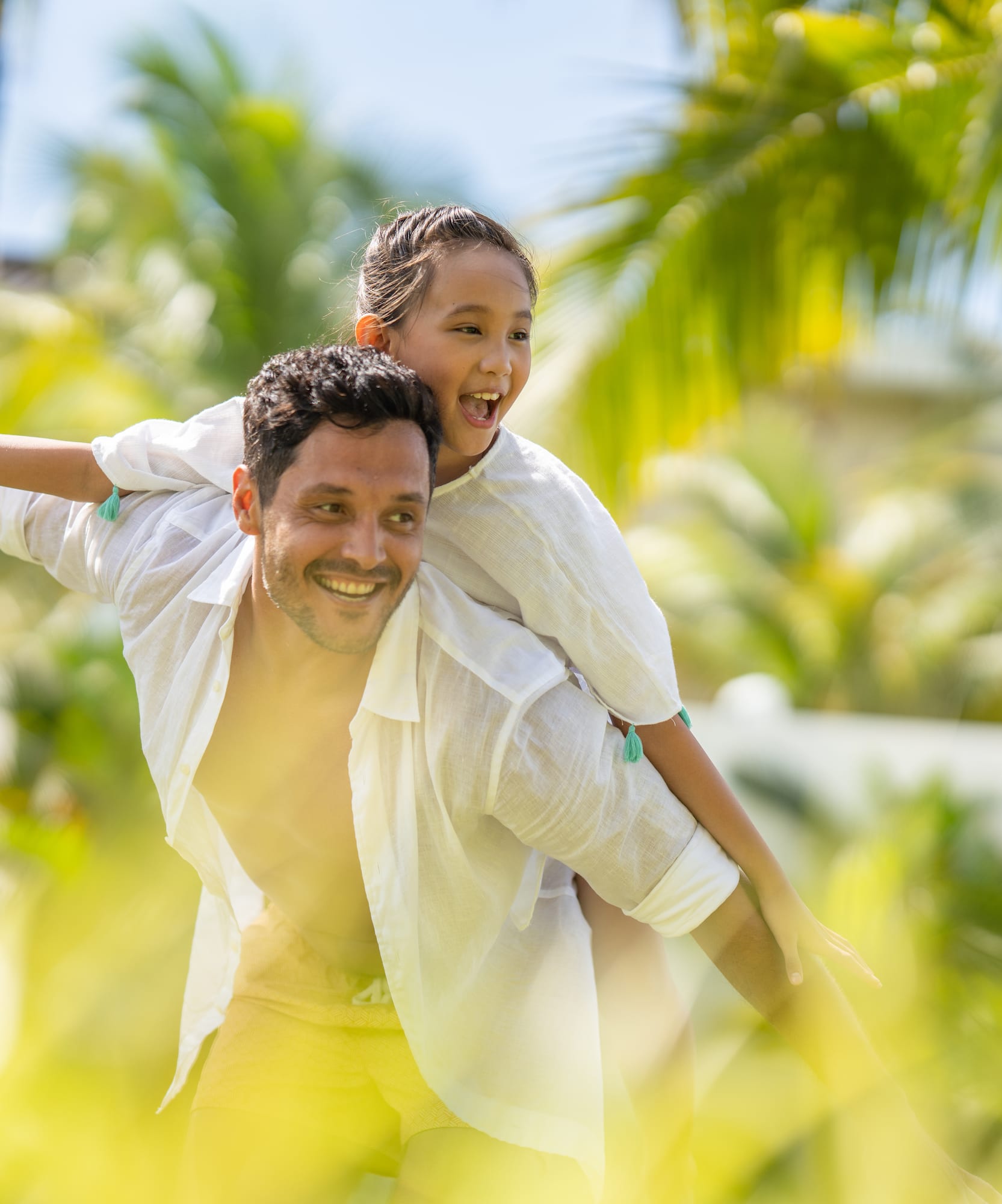Happy father and daughter on piggyback ride at tropical resort.