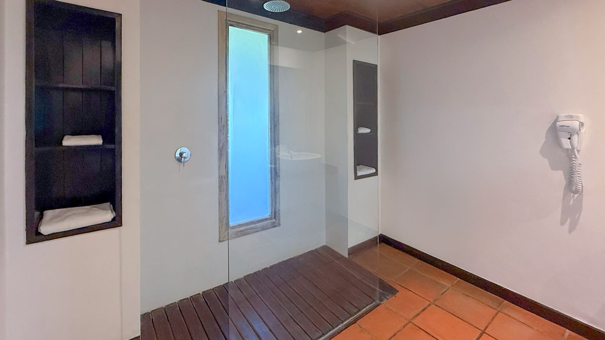 Modern walk-in glass shower with wooden floor and terracotta tiles.