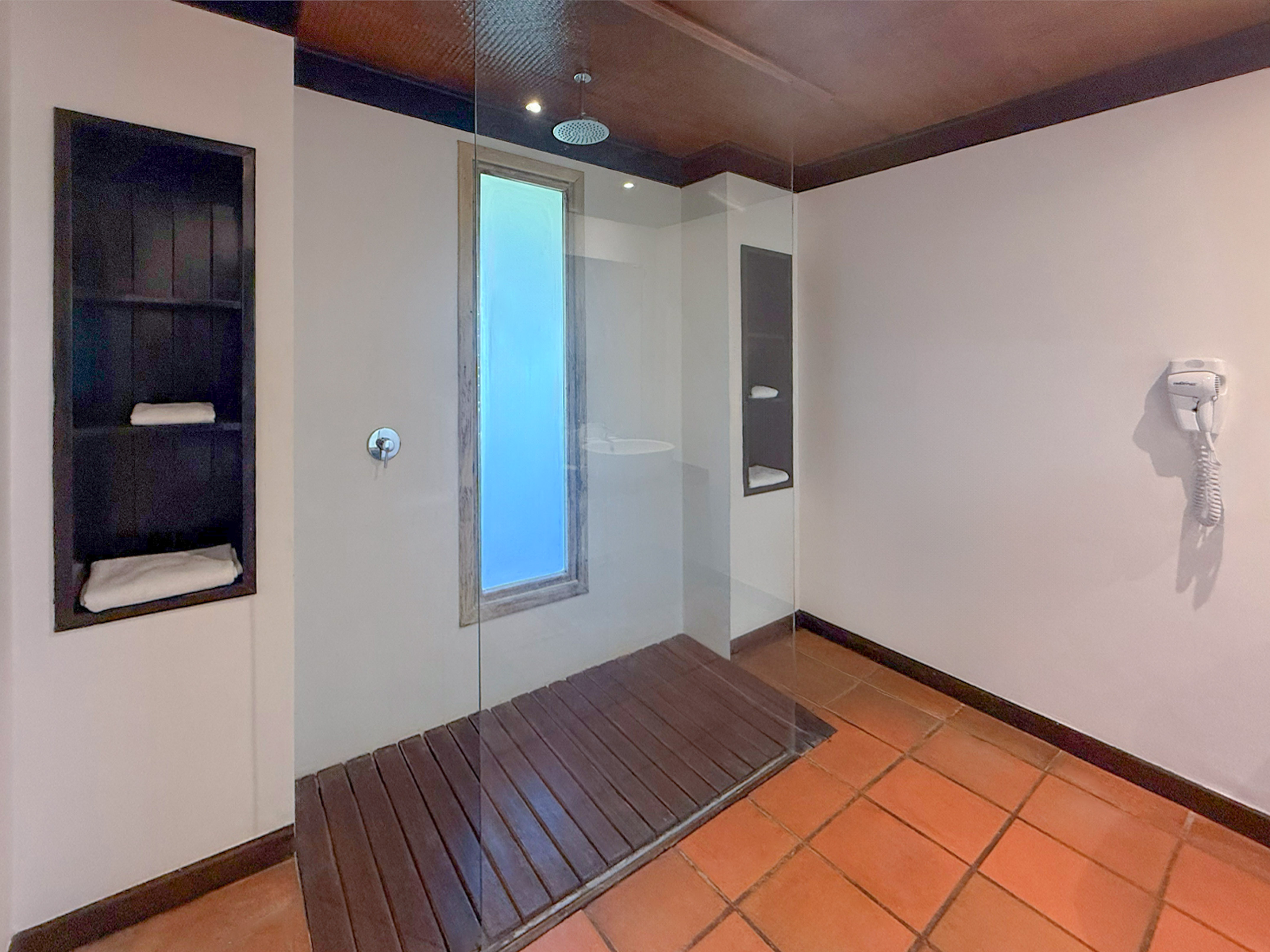 Modern walk-in glass shower with wooden floor and terracotta tiles.