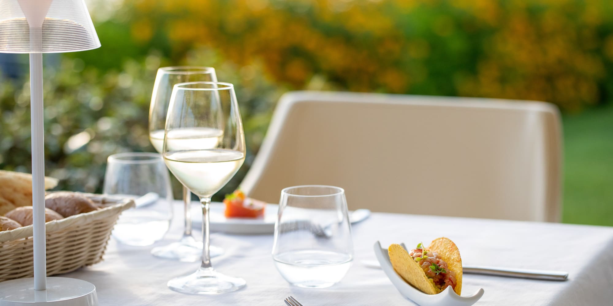 a taco in a shell on a table with wine glasses and a basket