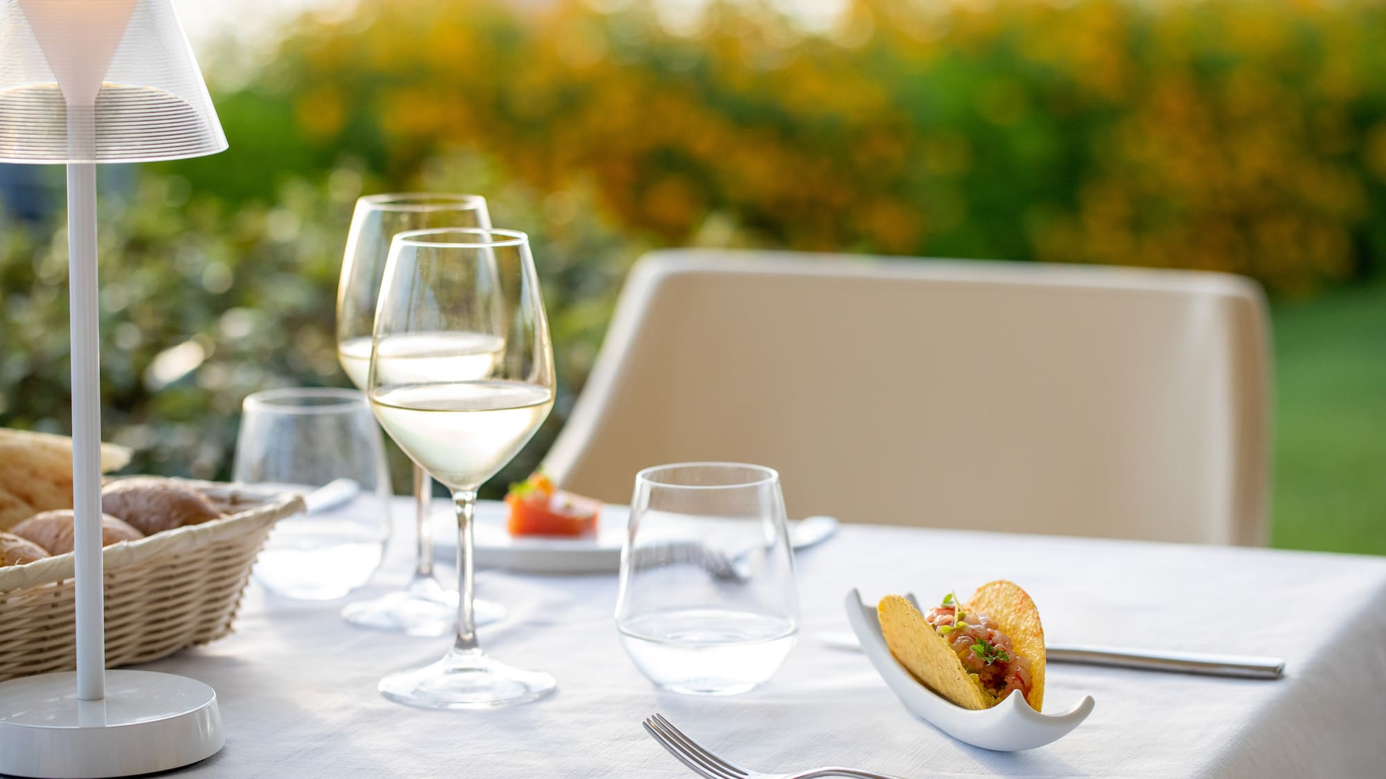 a taco in a shell on a table with wine glasses and a basket
