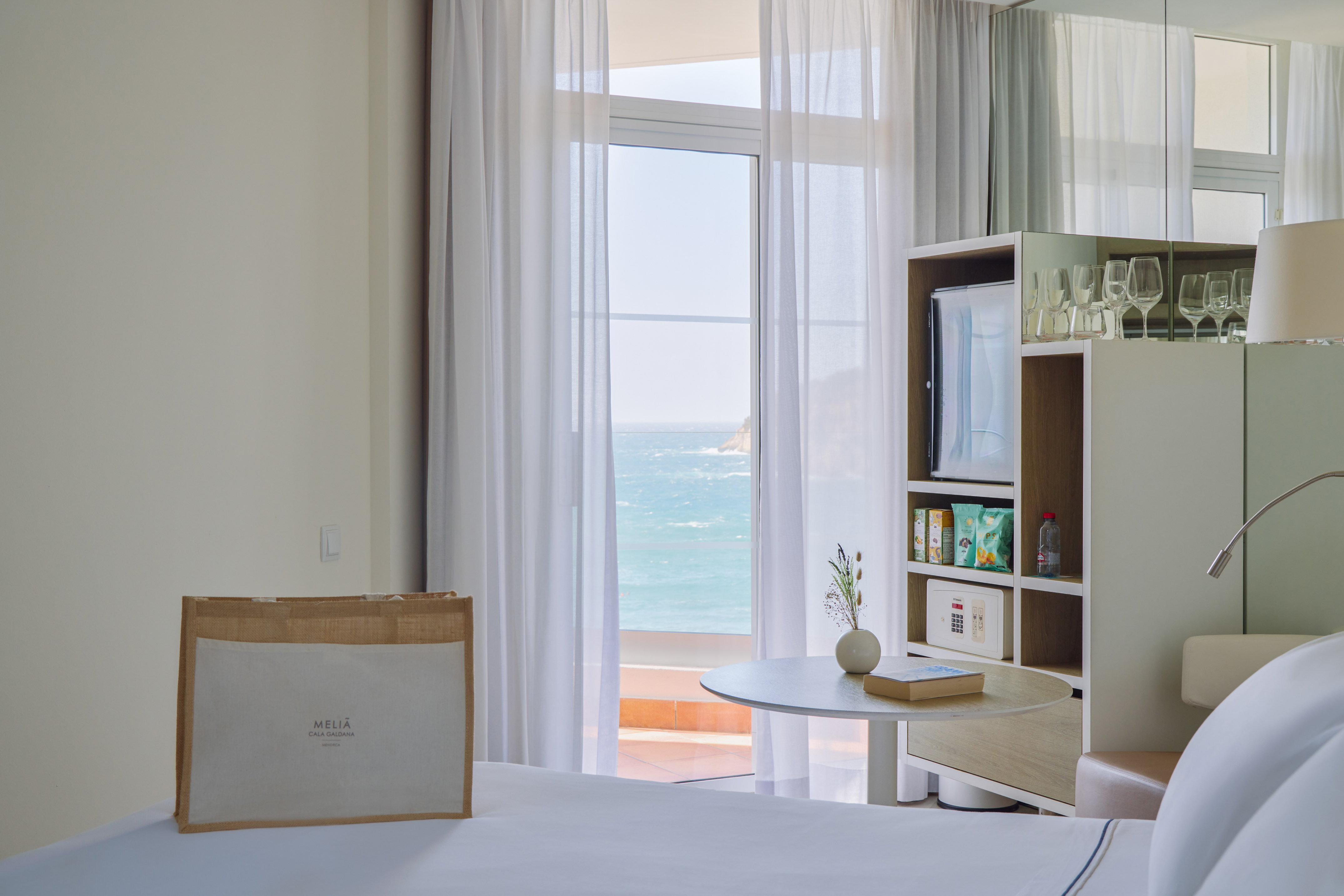 Meliã Cala Galdana hotel room, ocean view balcony, white bed.