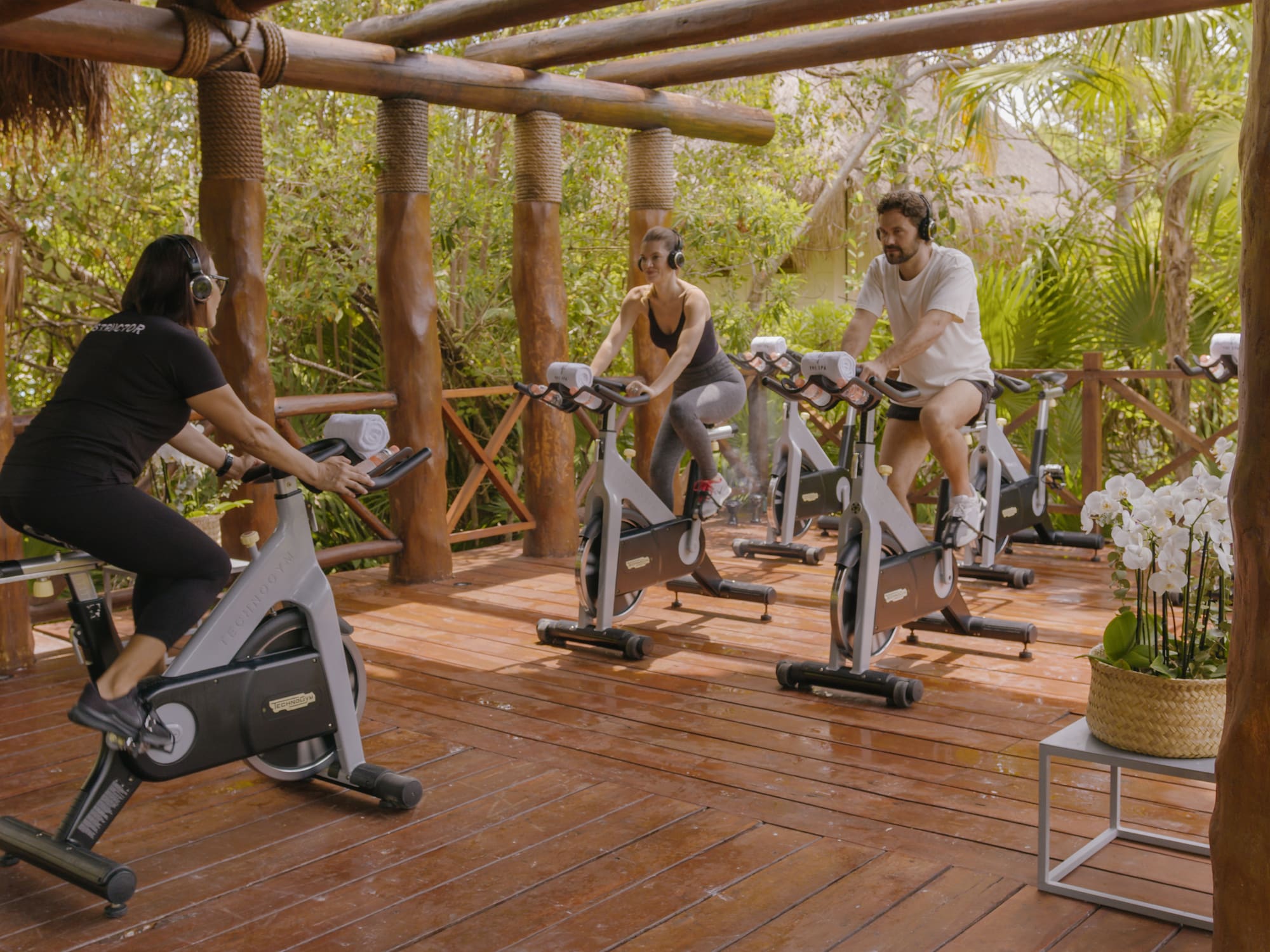 people on exercise bikes in a wood deck