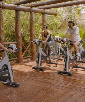 people on exercise bikes in a wood deck