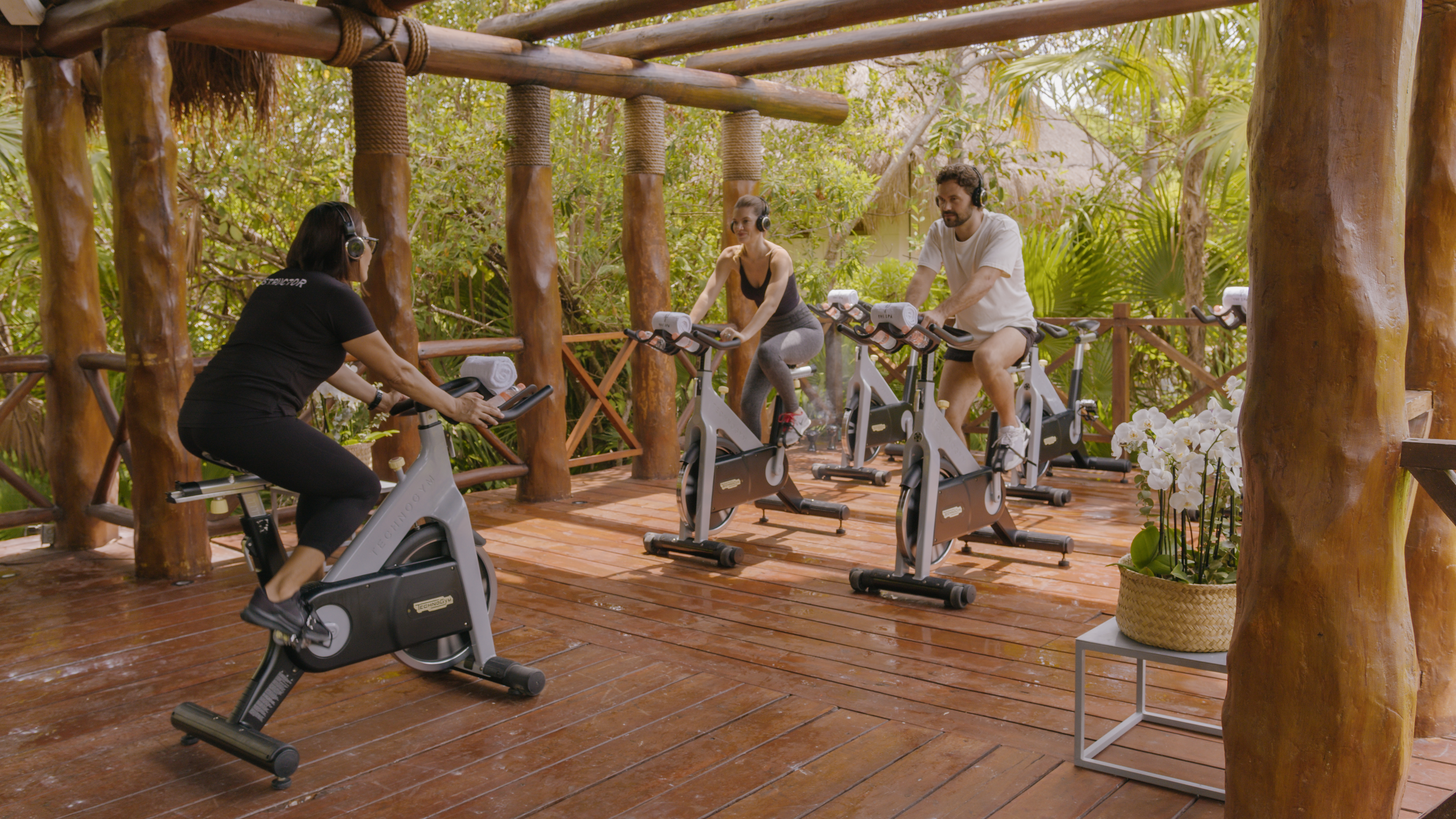 people on exercise bikes in a wood deck