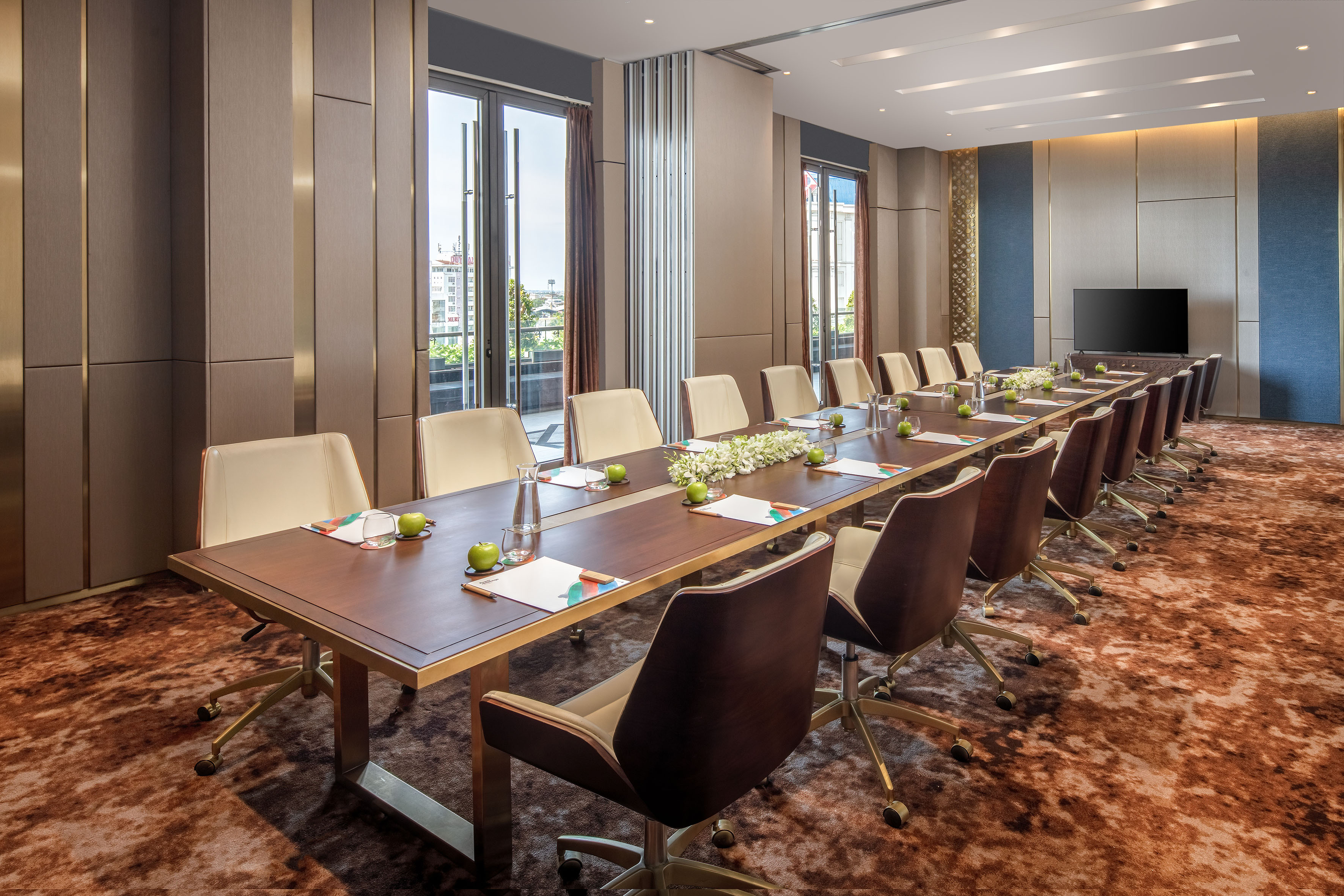 Luxury meeting room with long table, comfortable chairs, and large windows.