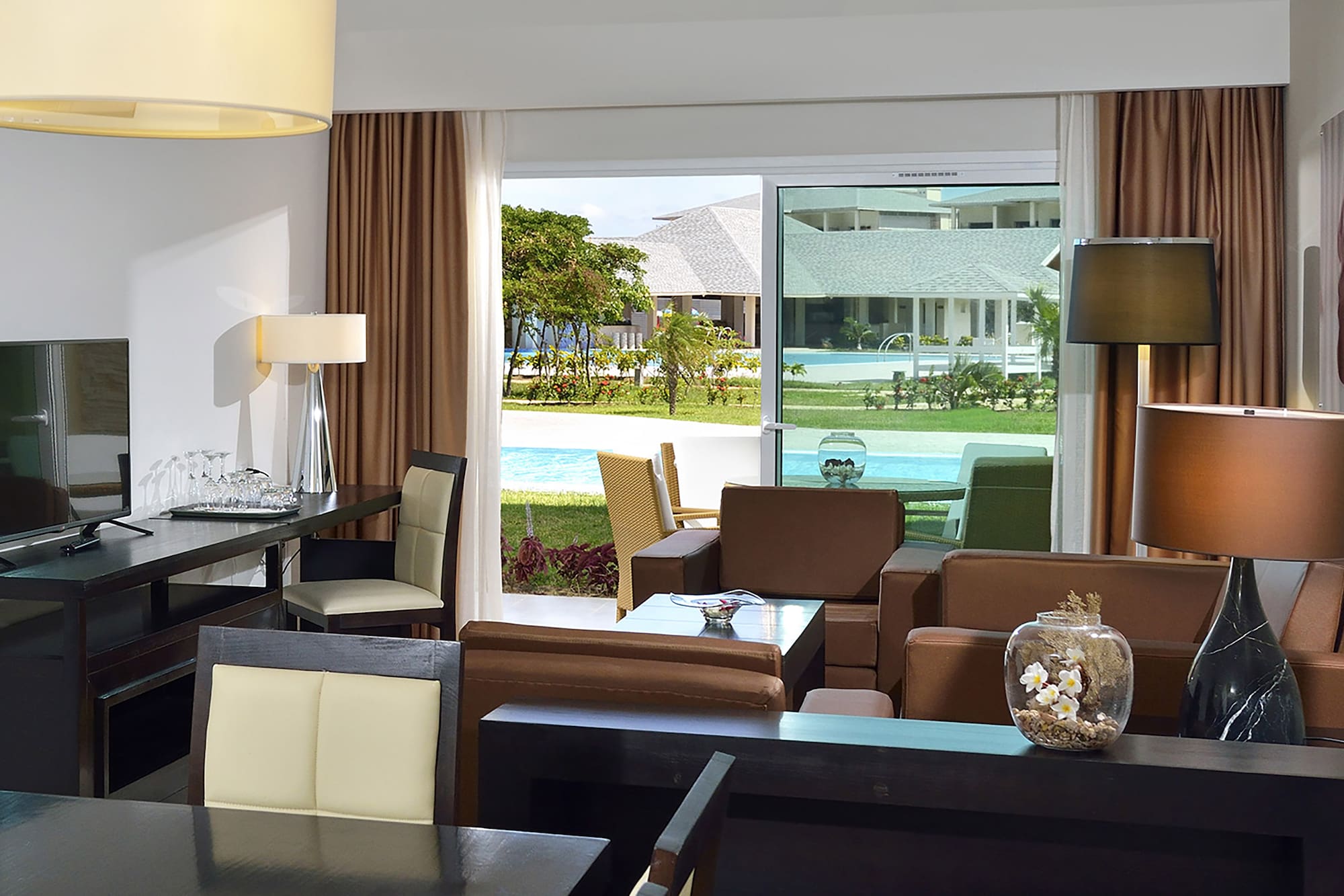 a room with a table and chairs and a pool outside