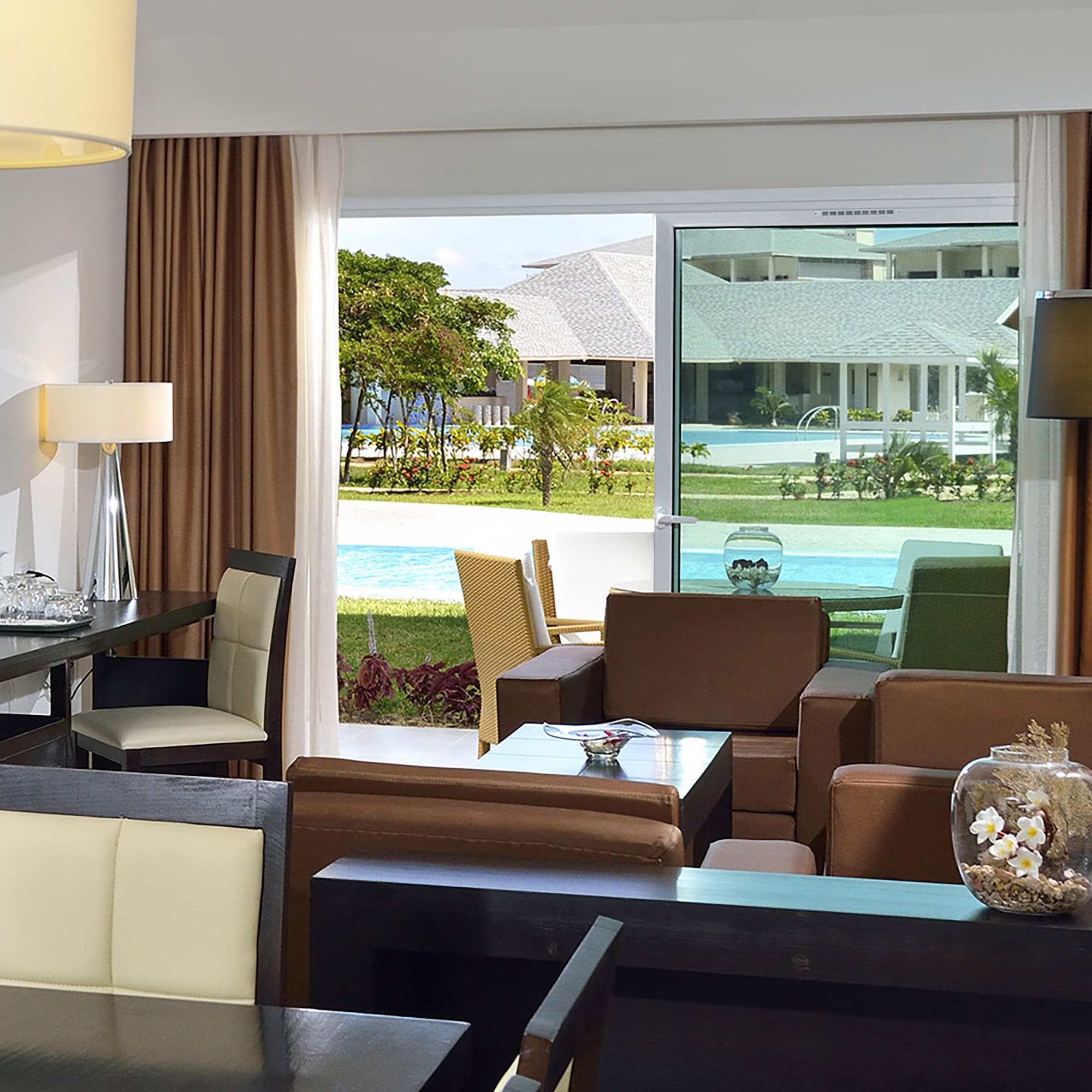 a room with a table and chairs and a pool outside