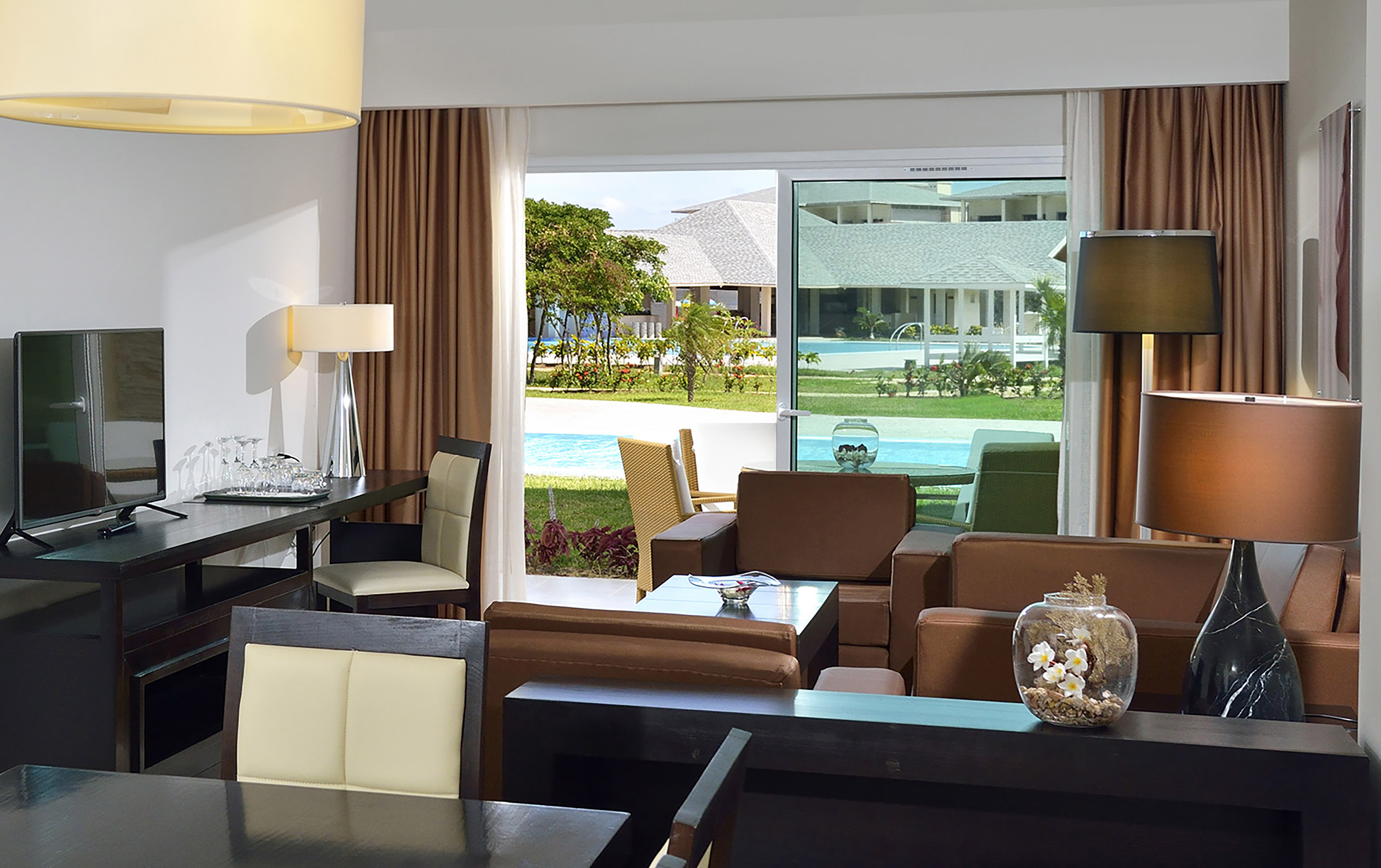 a room with a table and chairs and a pool outside