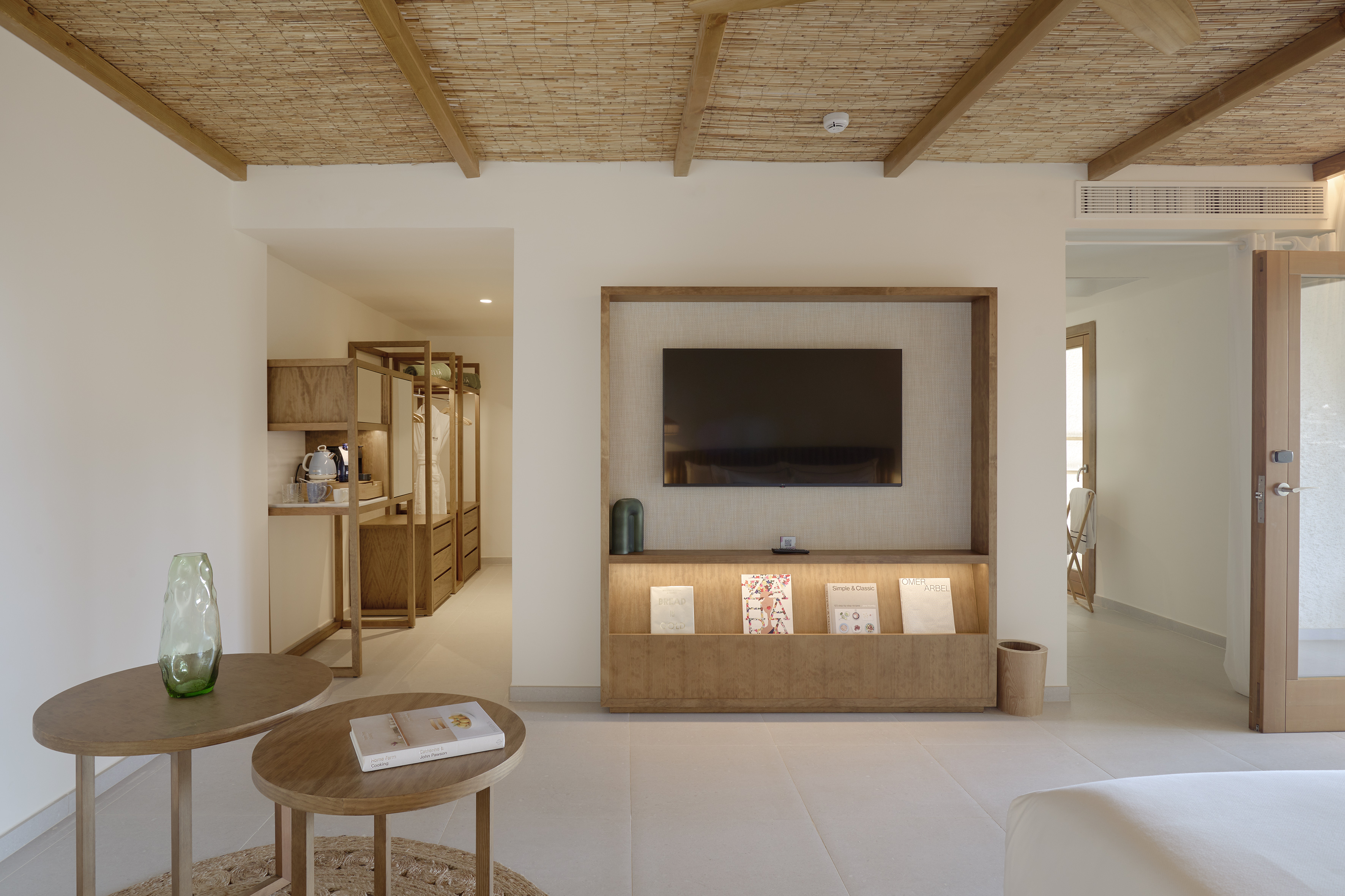 Hotel suite with wooden TV unit, raffia ceiling, and minimalist design.