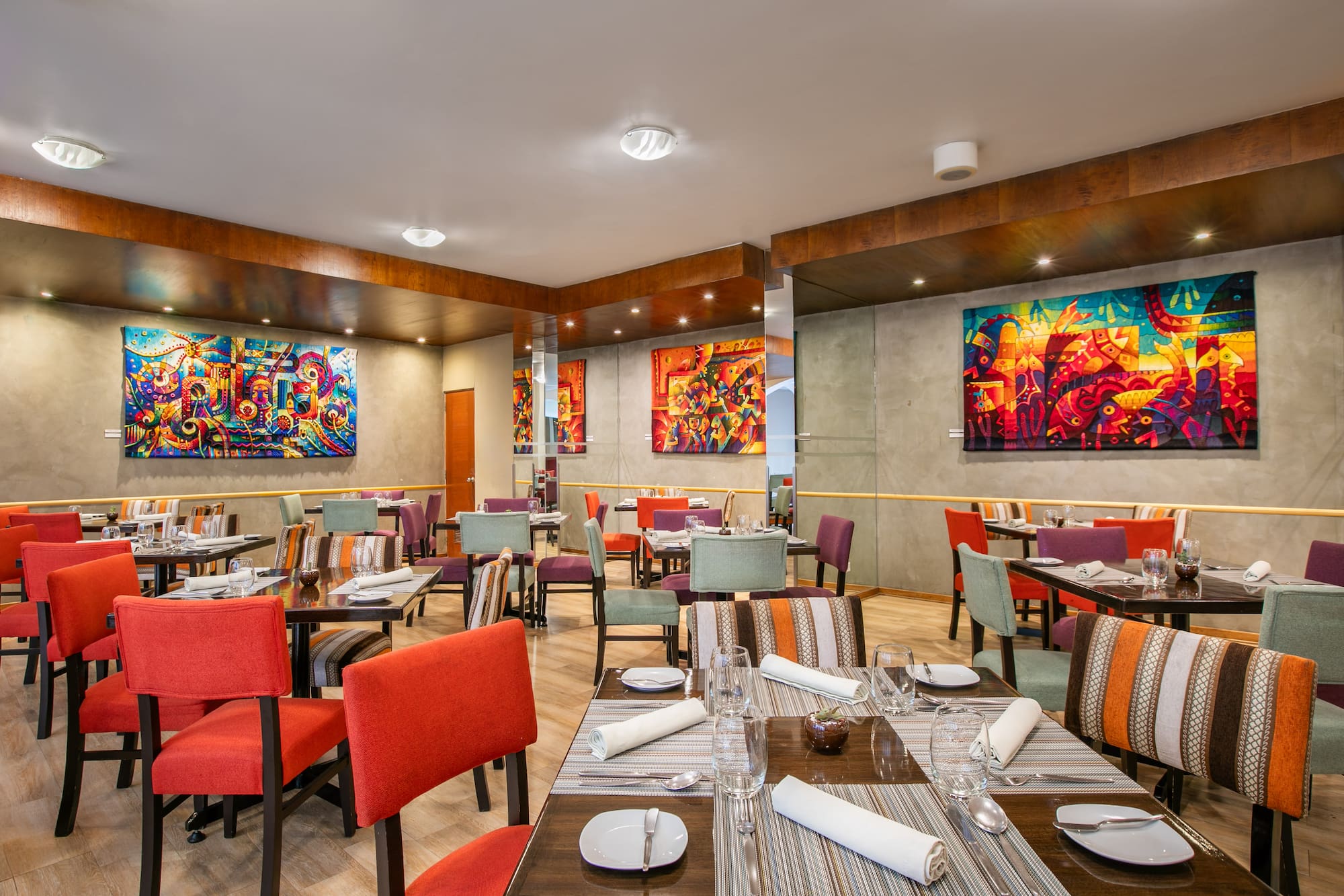 Vibrant modern restaurant dining room with colorful abstract art and set tables.