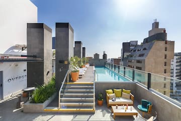 a rooftop pool with chairs and a table