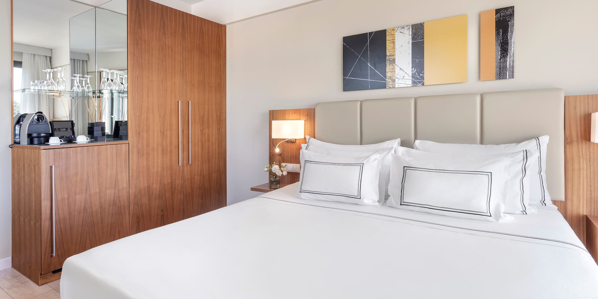 a bed with white sheets and a lamp next to a mirror