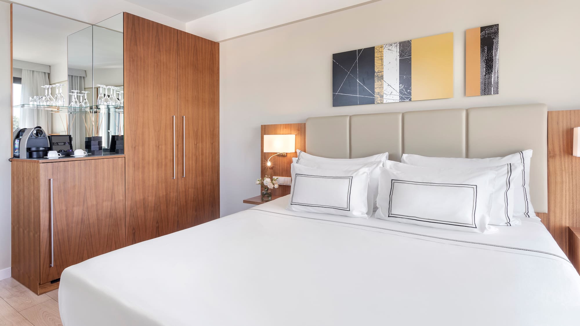 a bed with white sheets and a lamp next to a mirror