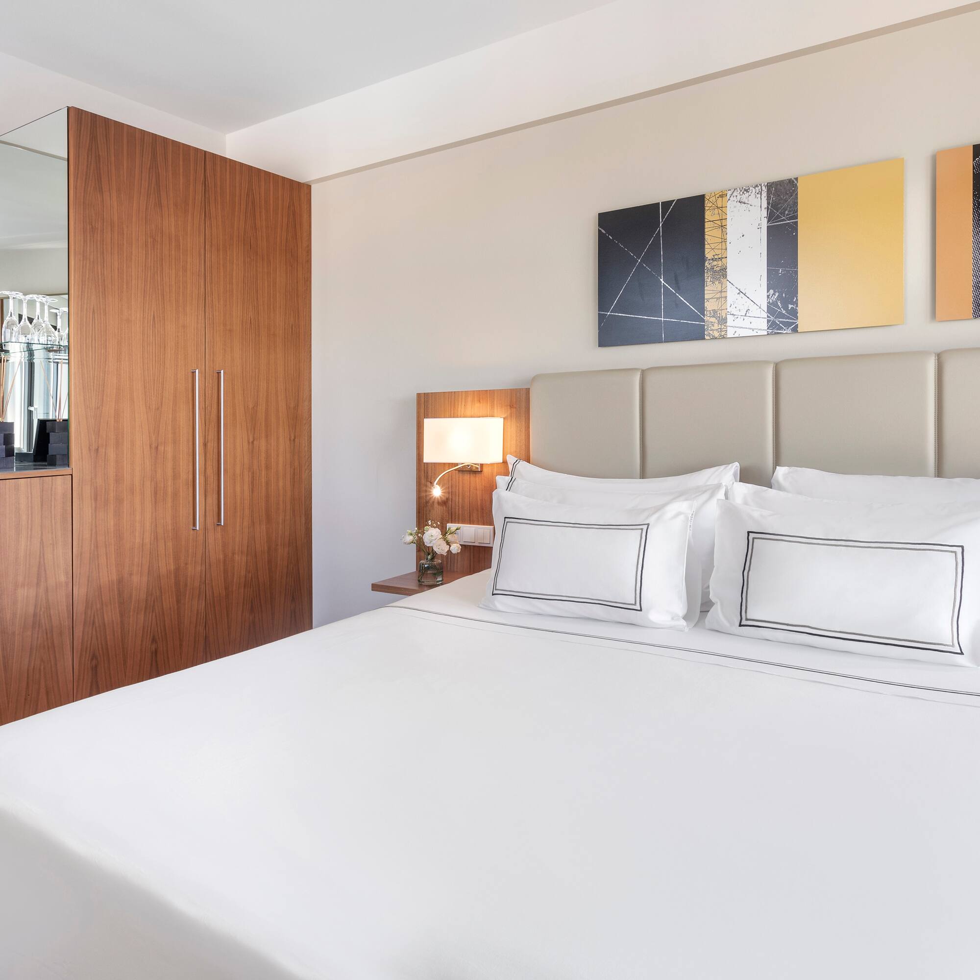 a bed with white sheets and a lamp next to a mirror