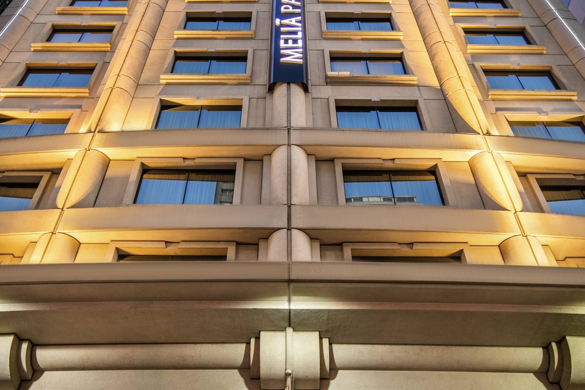 Meliá Paulista hotel with Brazilian flag, vertical sign, and stone facade in São Paulo.