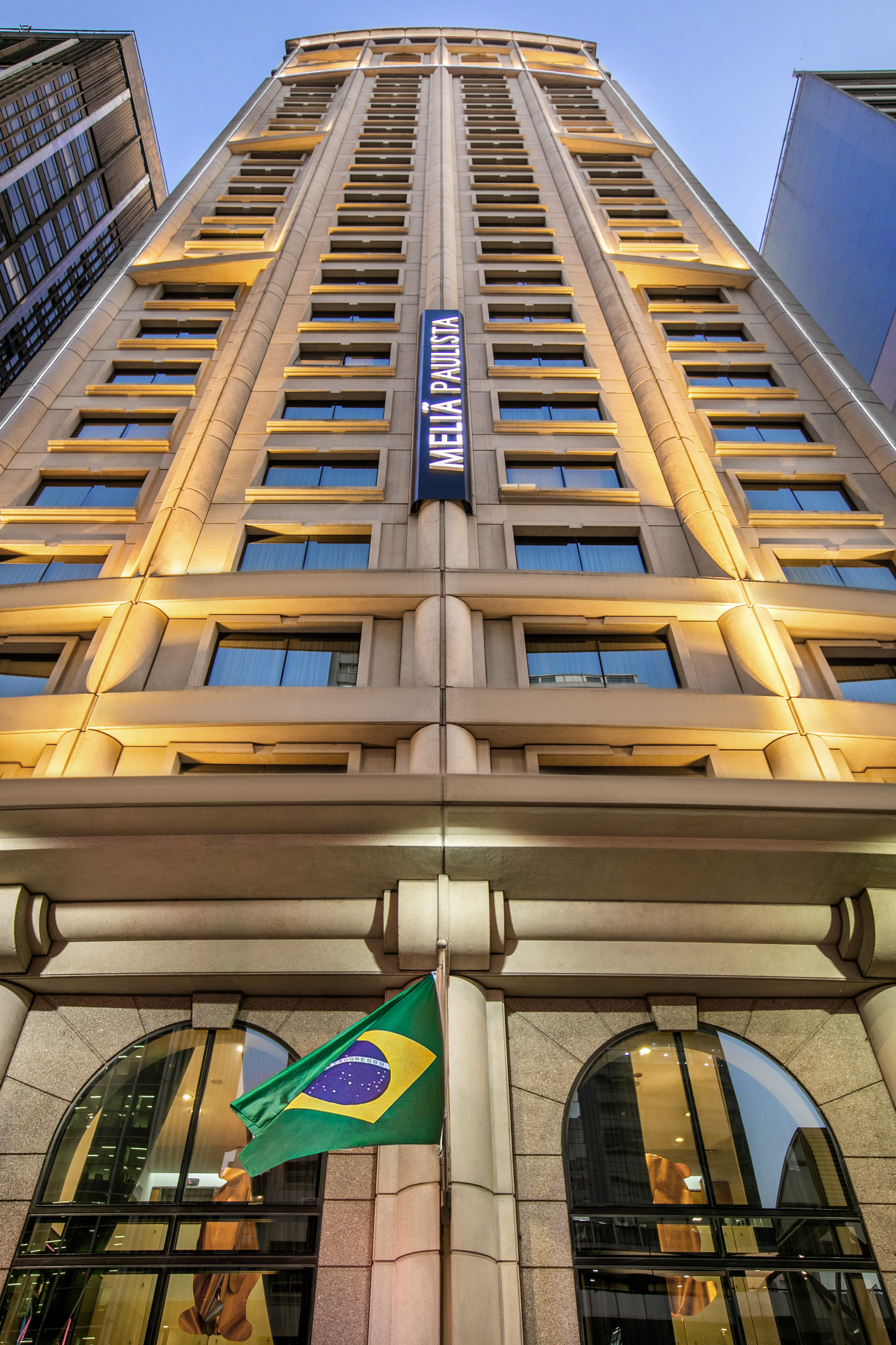 Meliá Paulista hotel with Brazilian flag, vertical sign, and stone facade in São Paulo.