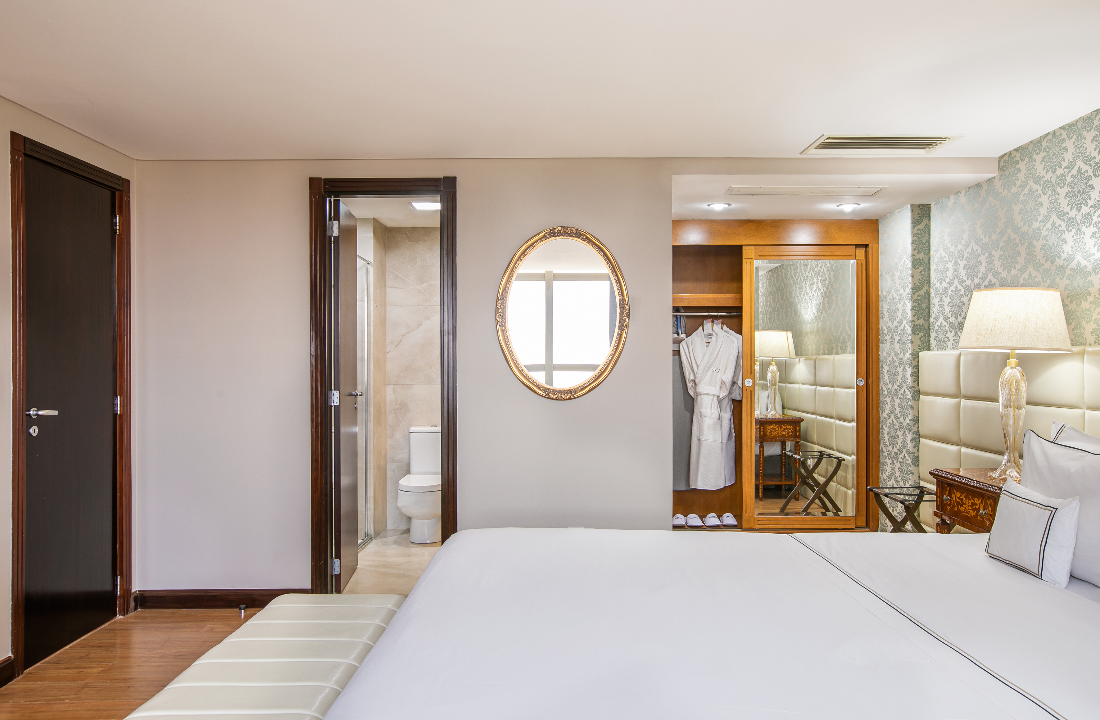 Luxury hotel bedroom with bed, ensuite bathroom, wardrobe, and mirror.