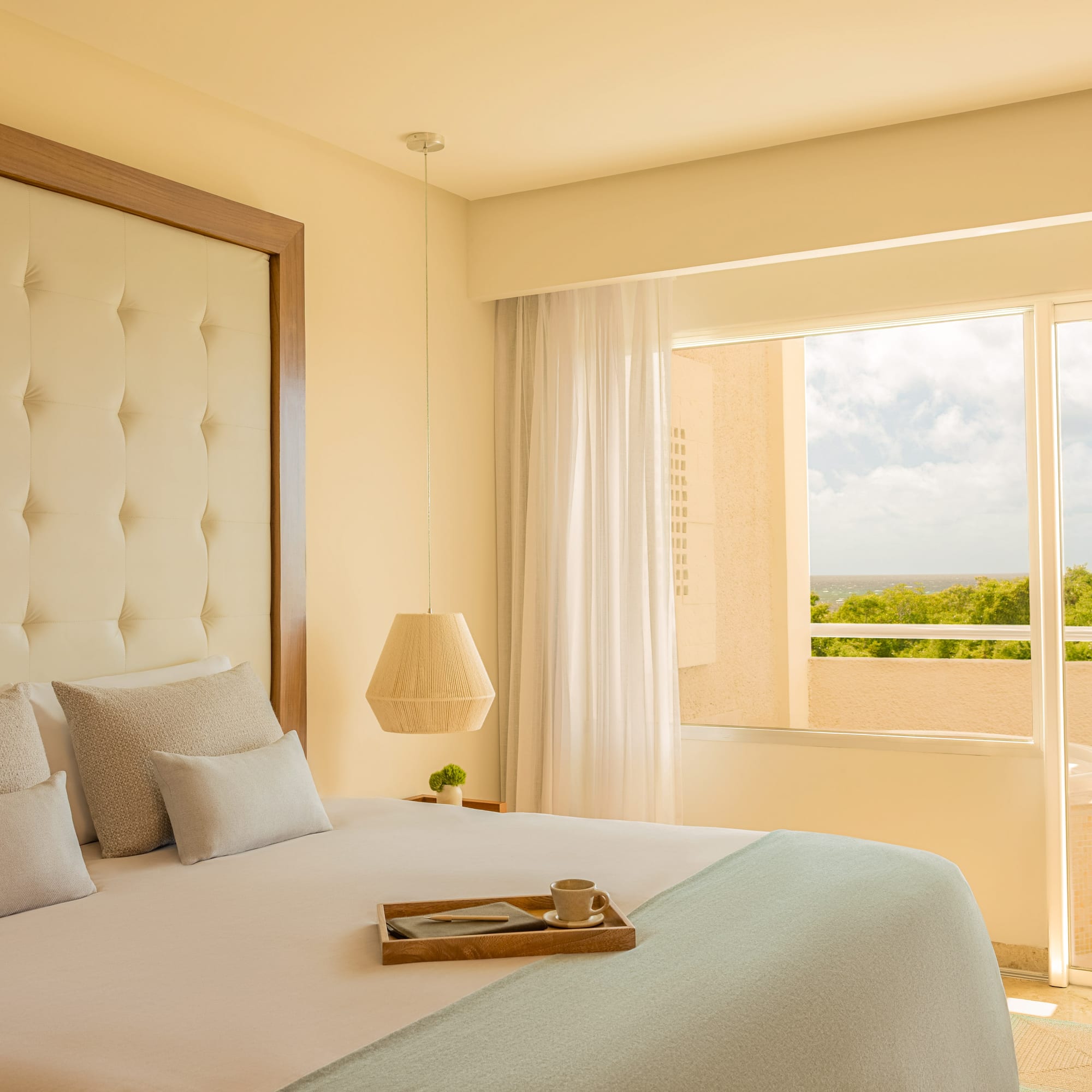 Modern hotel bedroom with bed, balcony, hot tub, and ocean view.