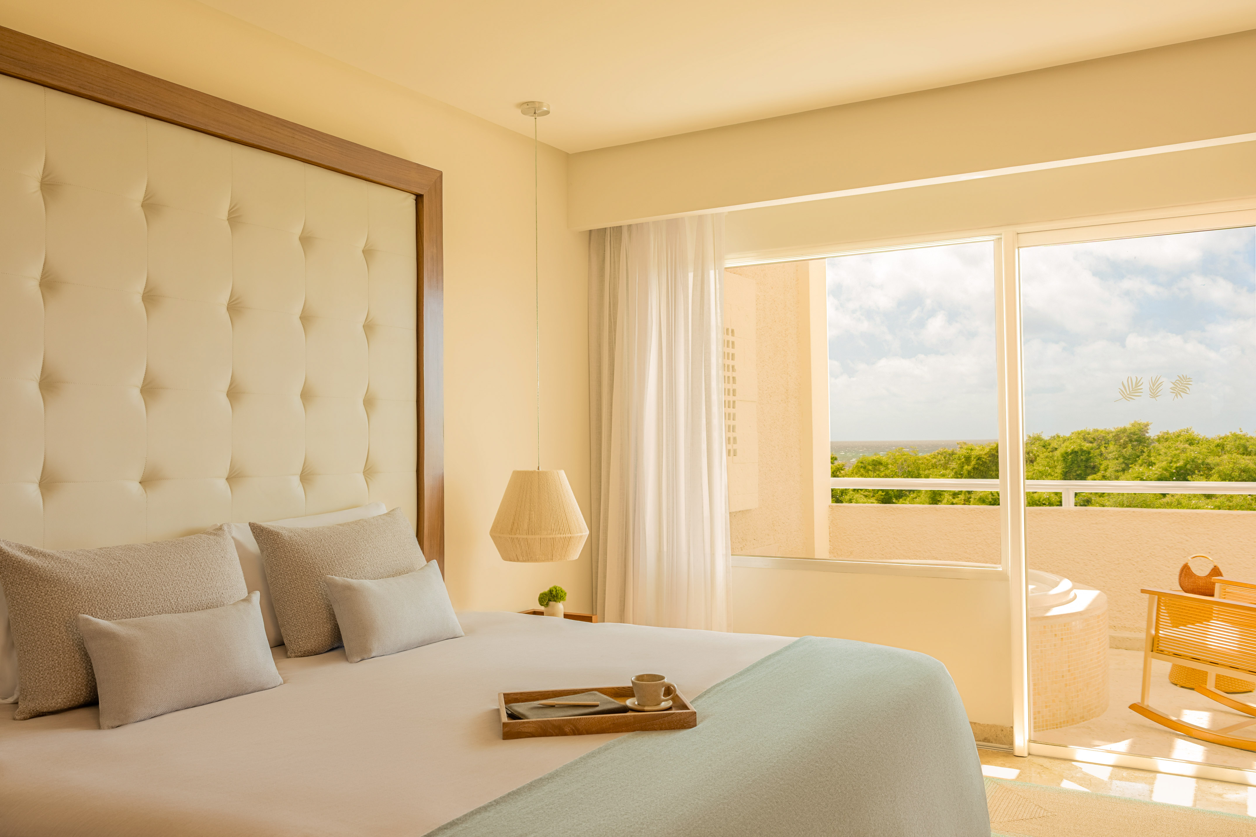 Hotel bedroom with balcony ocean view, tufted bed, and outdoor hot tub.