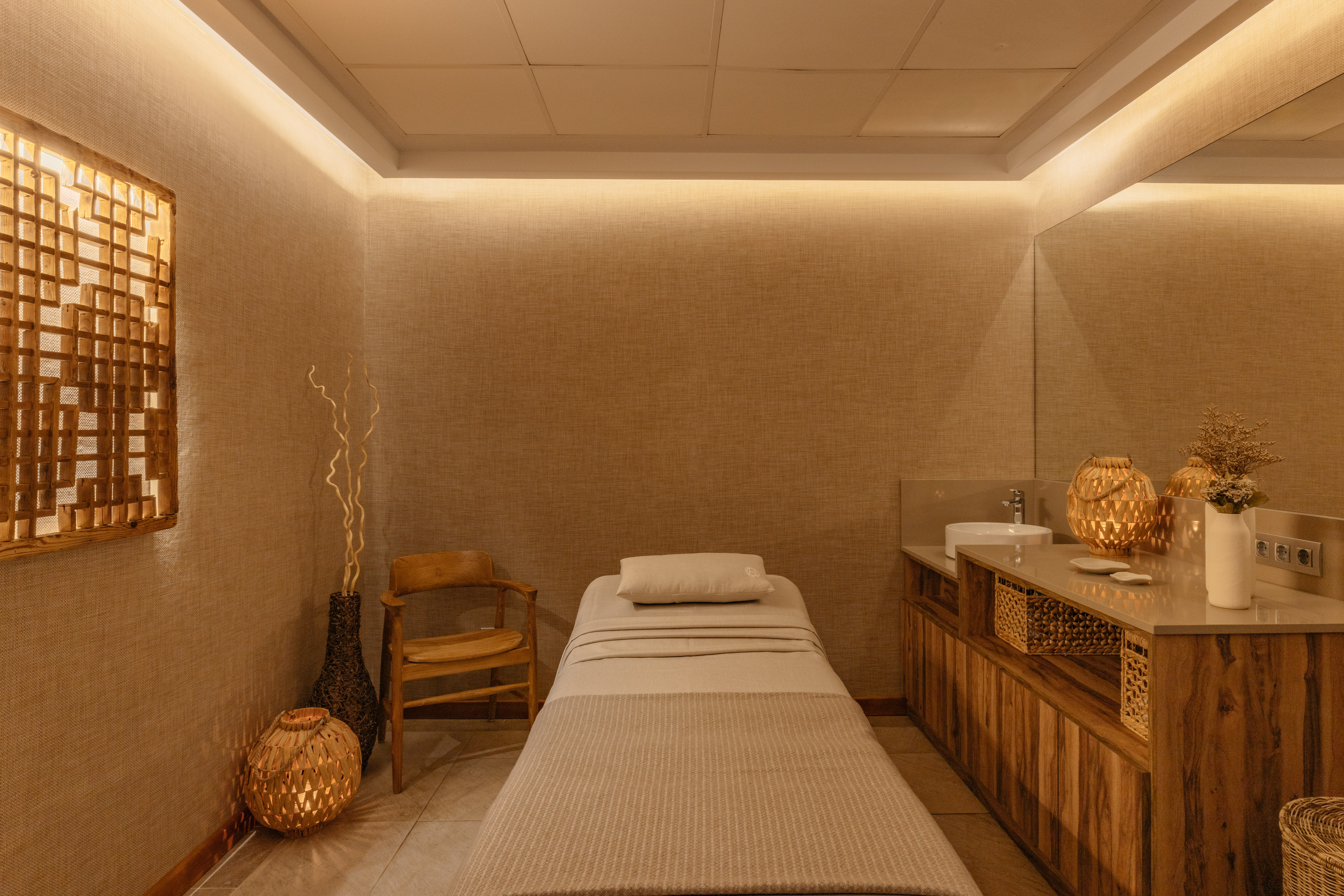 Spa treatment room with massage bed, wooden decor, and warm lighting.