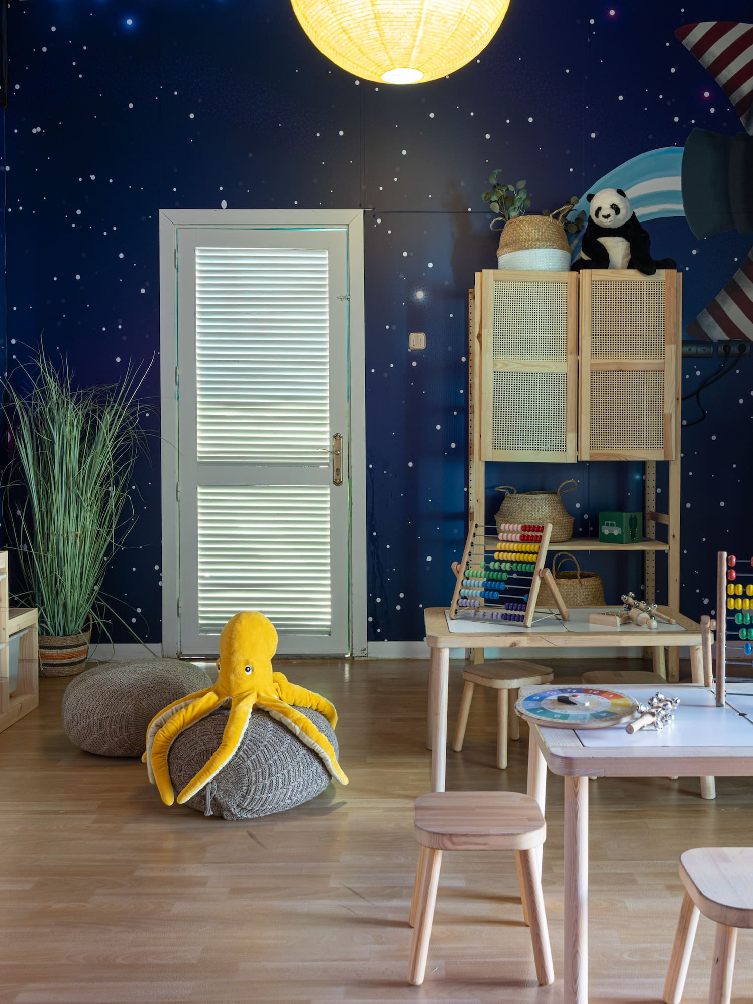 Kids' space-themed playroom with rocket mural, wooden furniture, abacus, and storage.