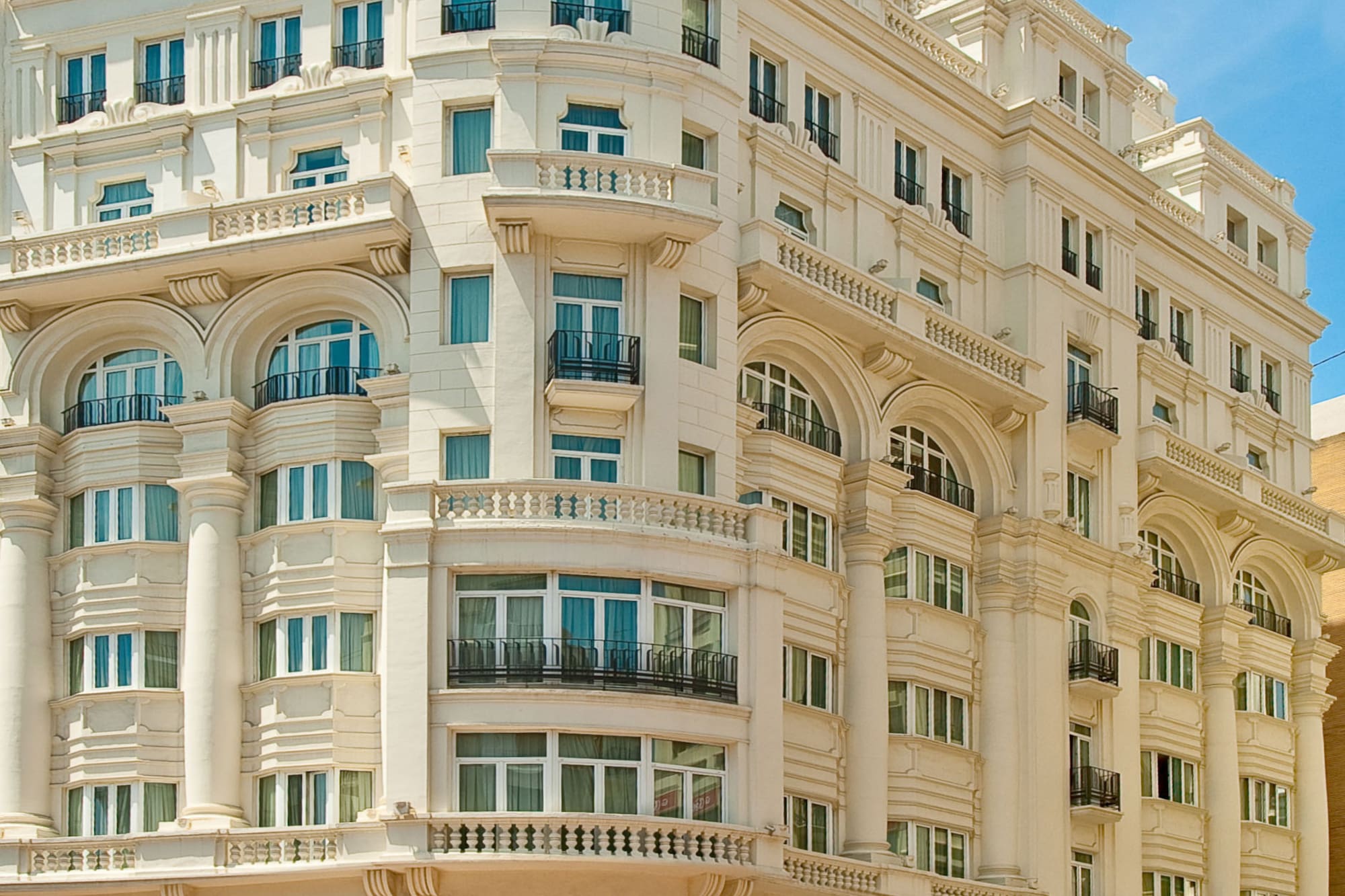 Ornate white Meliá Plaza hotel building with classical architecture and flags.