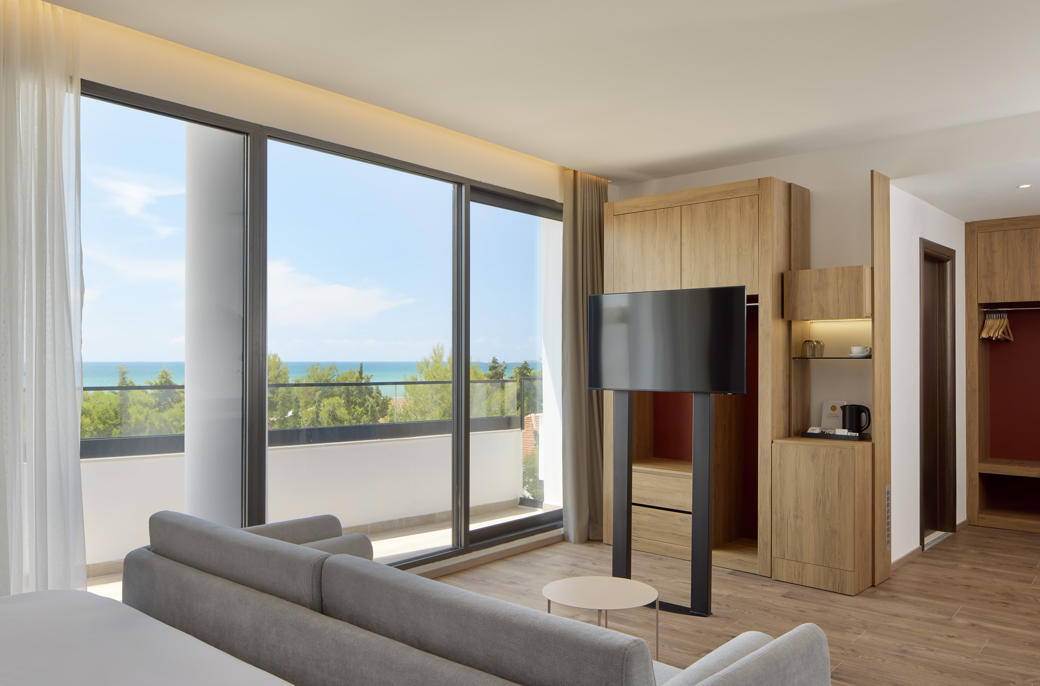 Bright modern hotel room with ocean view balcony and contemporary wooden decor.