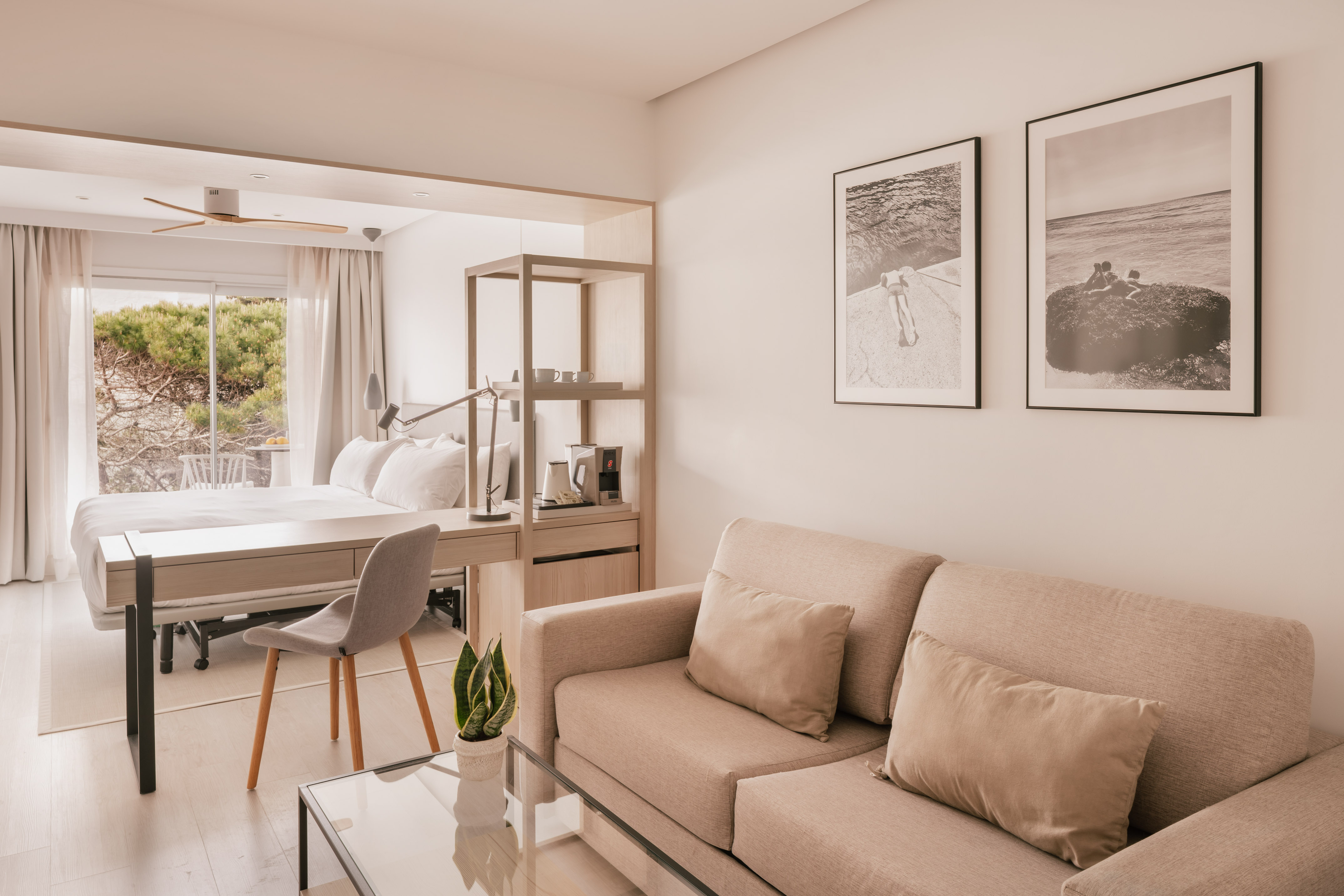 Suite hotel moderna con salón, dormitorio, escritorio y vista jardín.