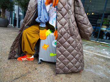 a person in a coat and a large coat with a suitcase