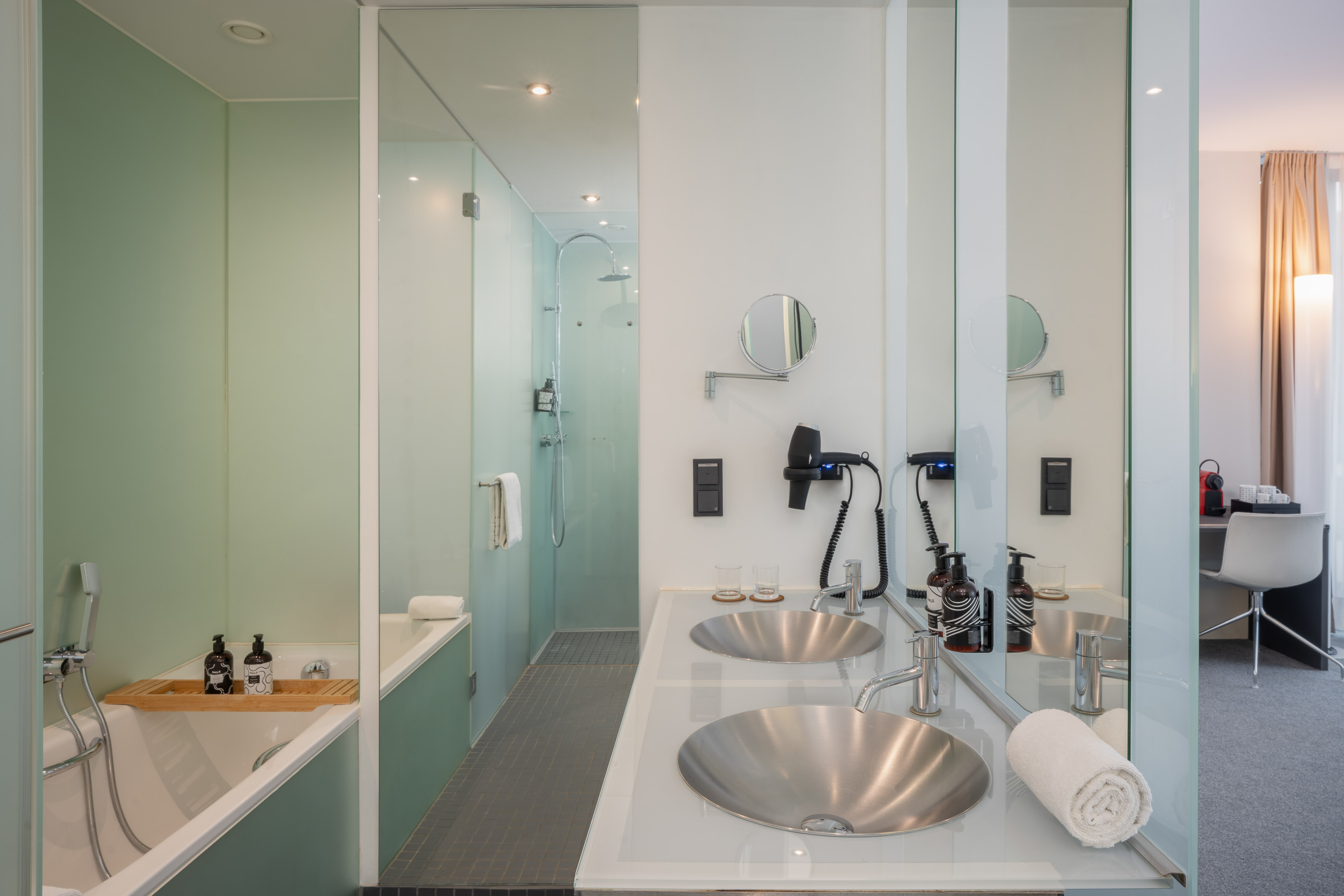Modern hotel bathroom with double vanity, glass shower, and bathtub.