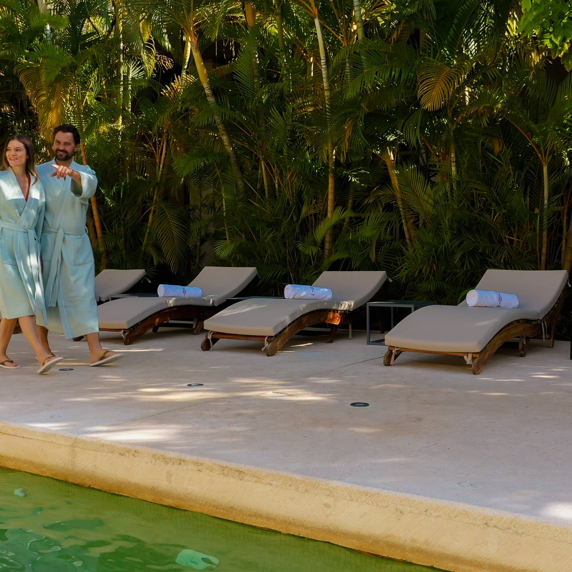 a man and woman standing near lounge chairs