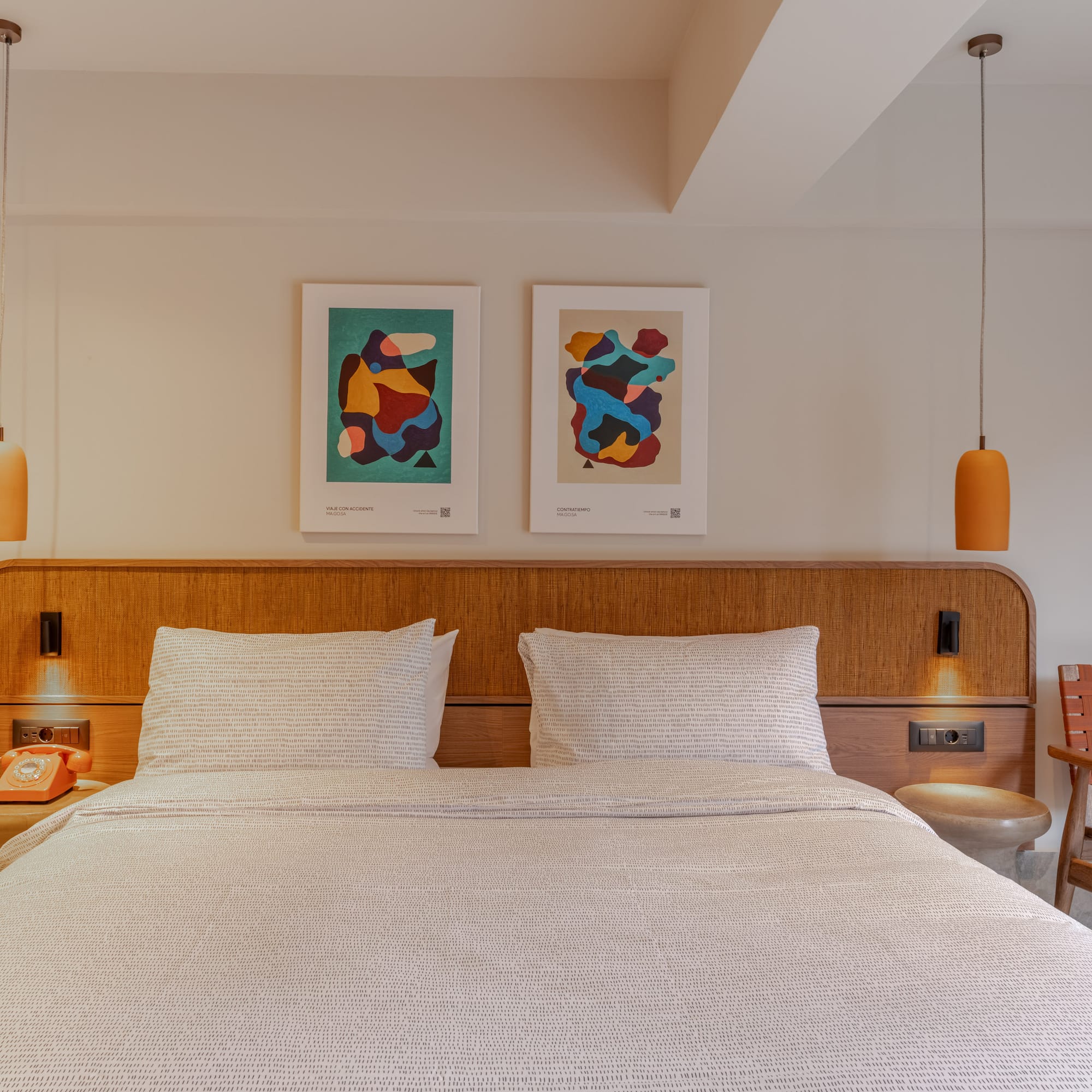 a bed with a wood headboard and two lamps above it