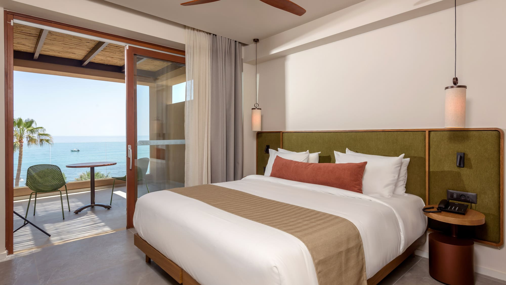 Modern hotel room with ocean view, private balcony, and king bed.