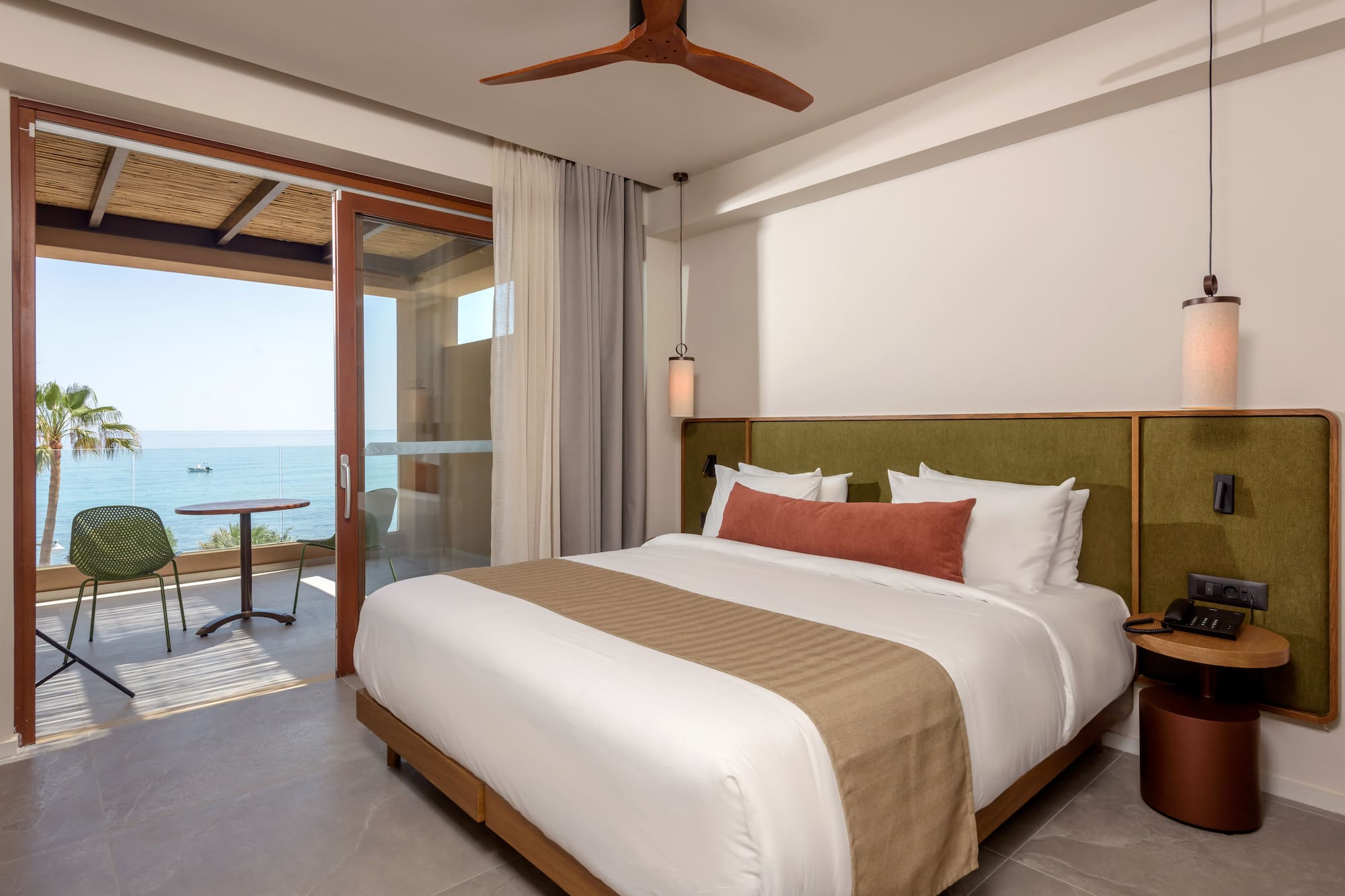 Modern hotel room with ocean view, private balcony, and king bed.