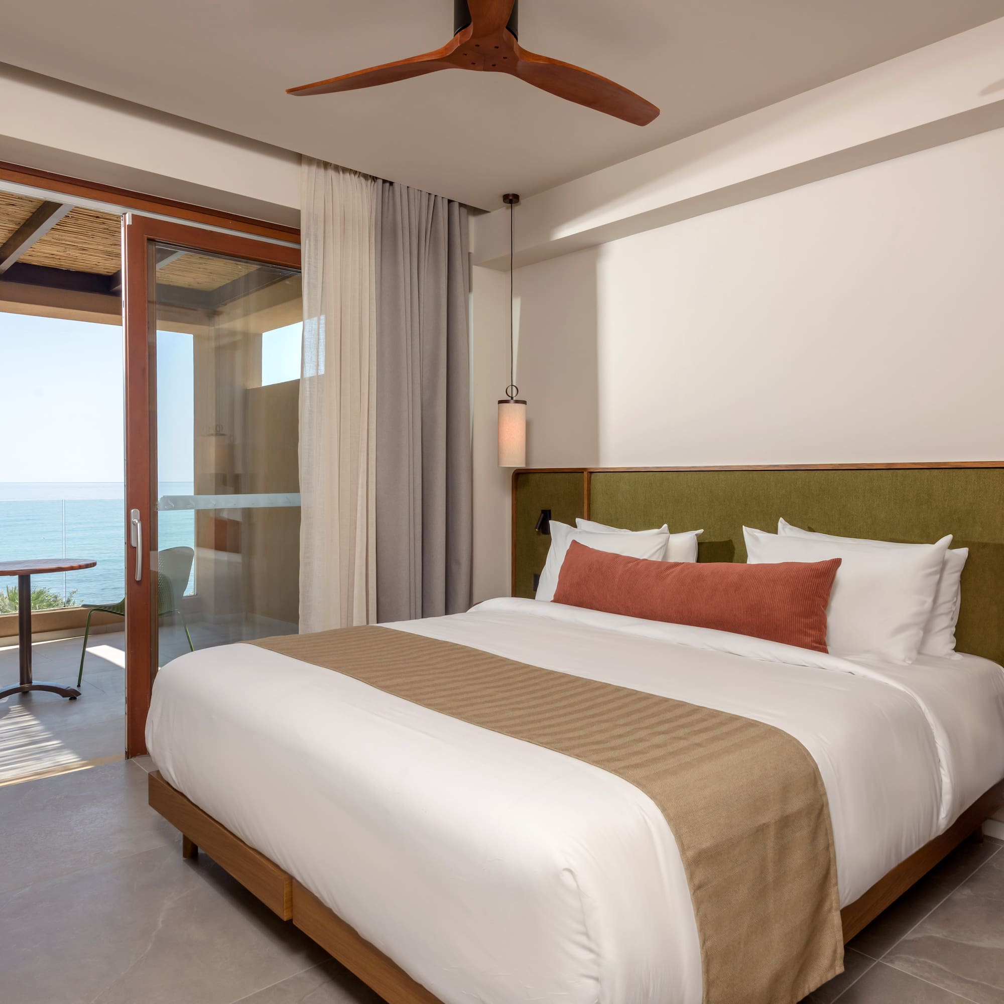 Modern hotel room with ocean view, private balcony, and king bed.