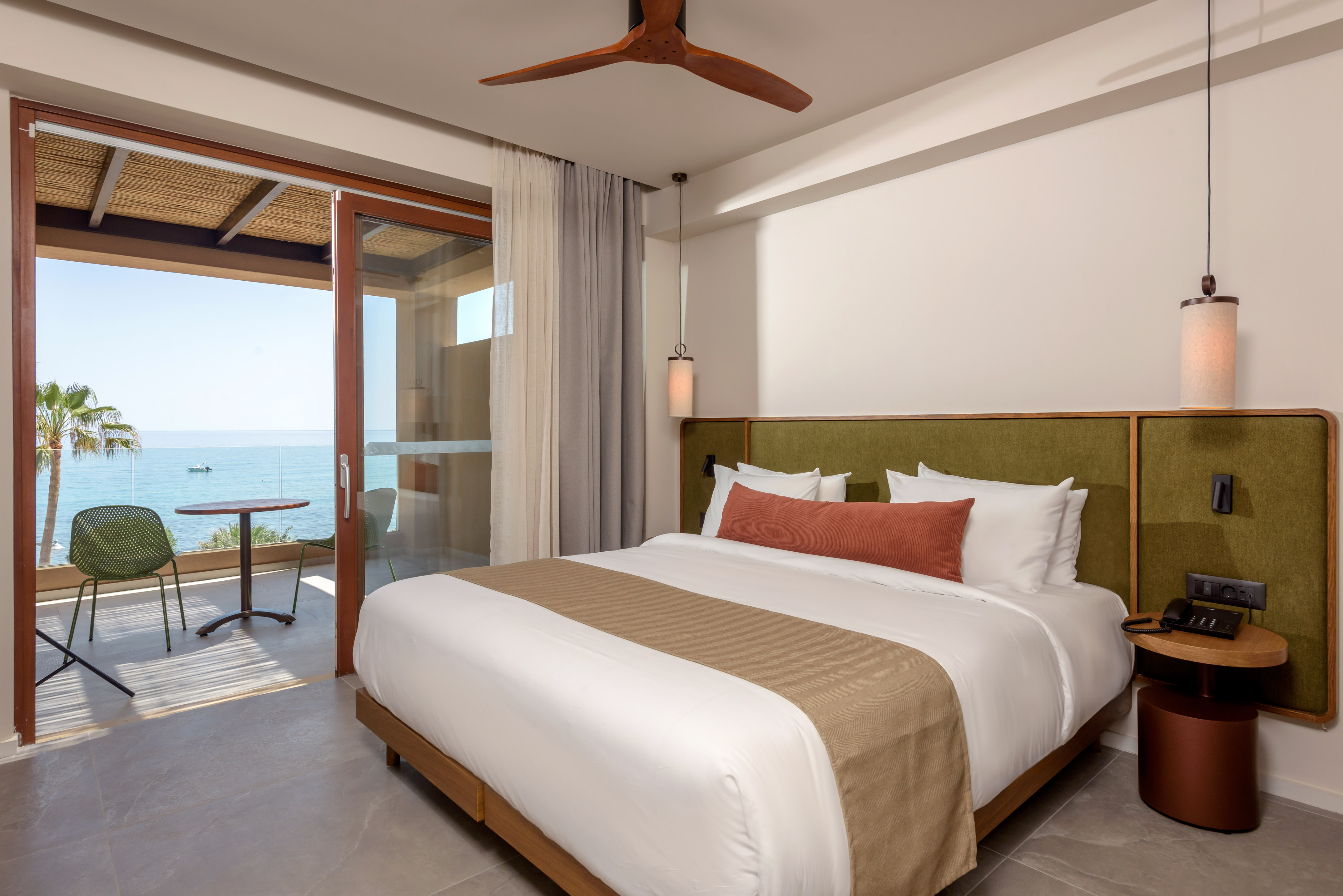 Modern hotel room with ocean view, private balcony, and king bed.