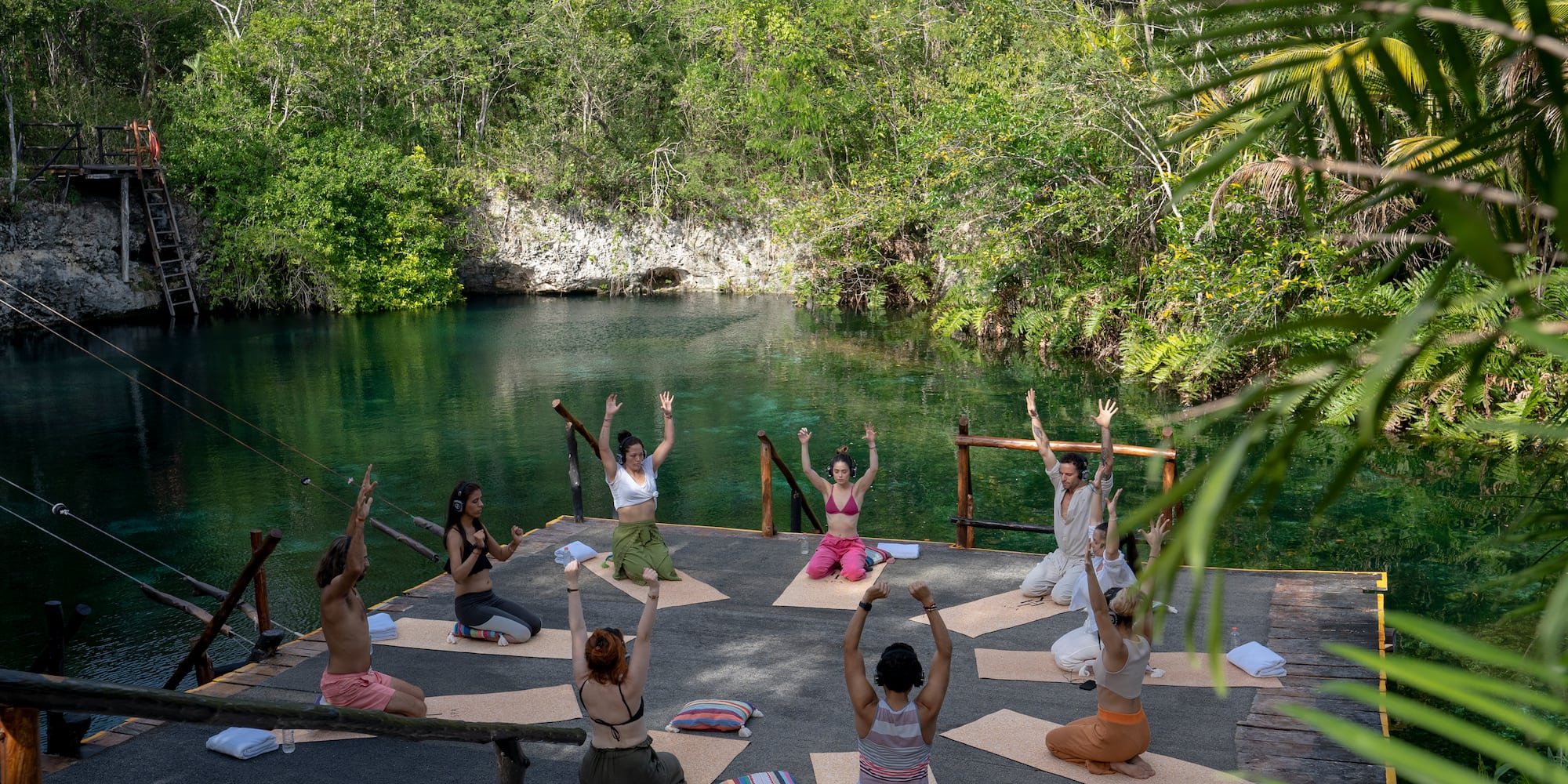 a group of people doing yoga outside by a body of water