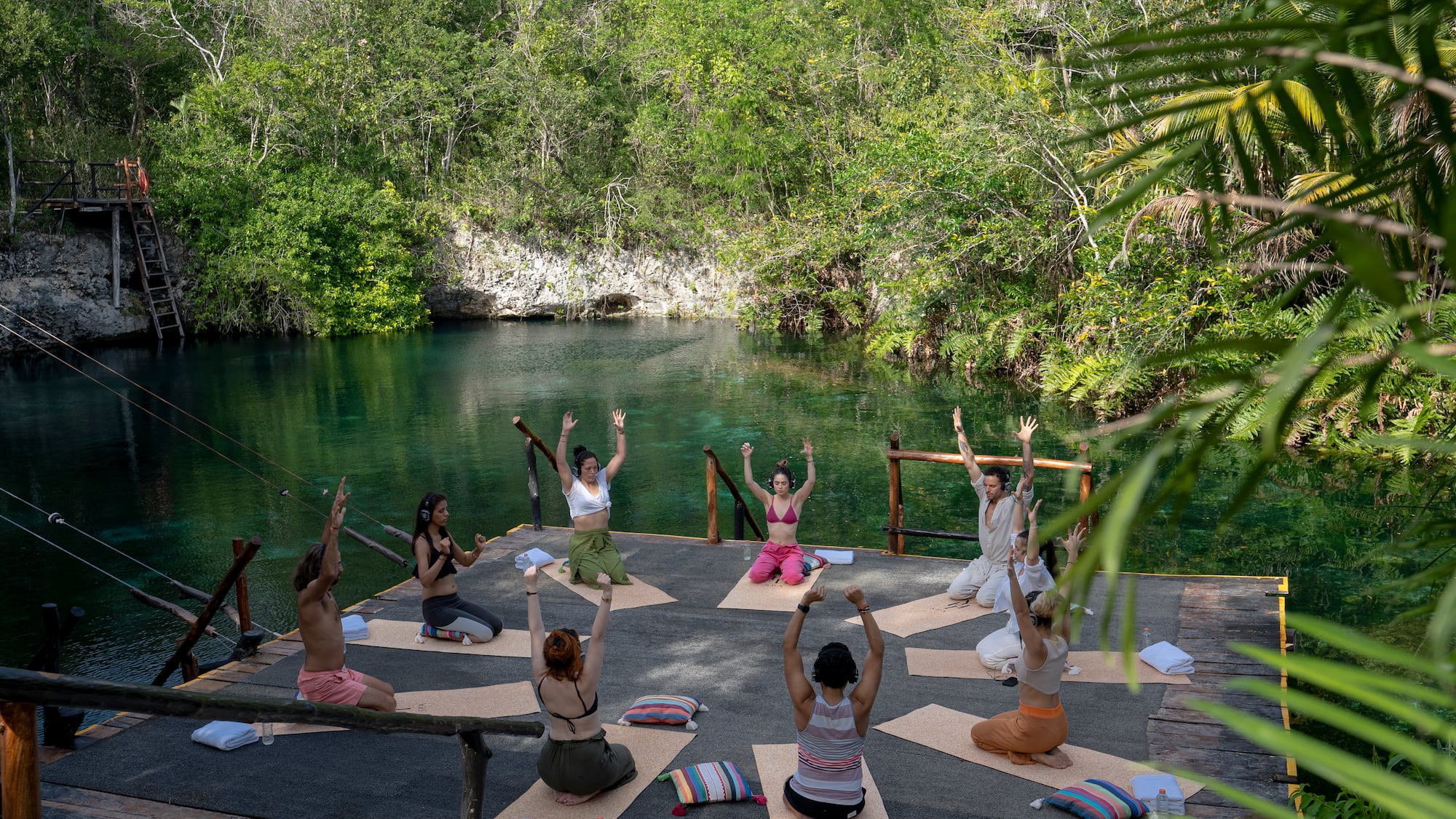 a group of people doing yoga outside by a body of water