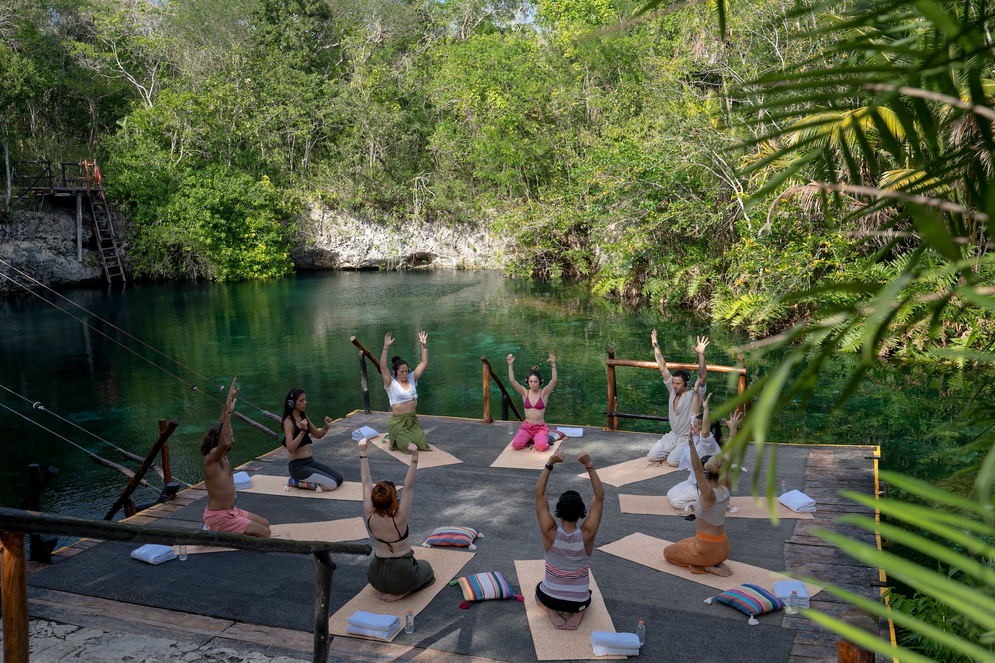 a group of people doing yoga outside by a body of water